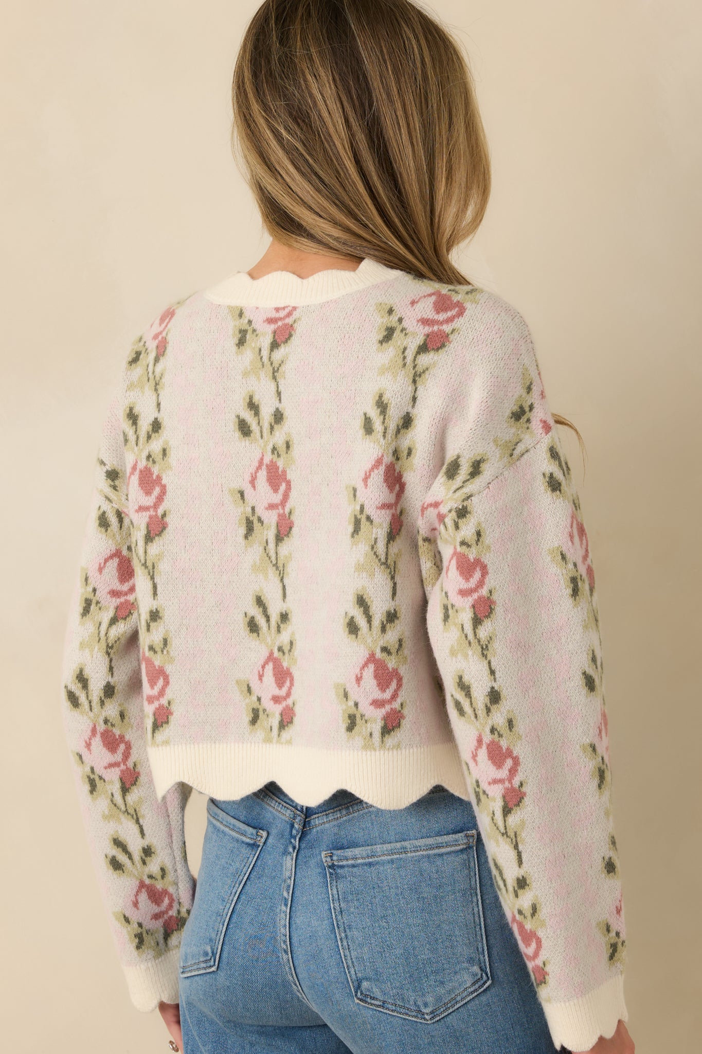Pink floral knit sweater with long sleeves and a relaxed, subtly cropped silhouette from the rear.