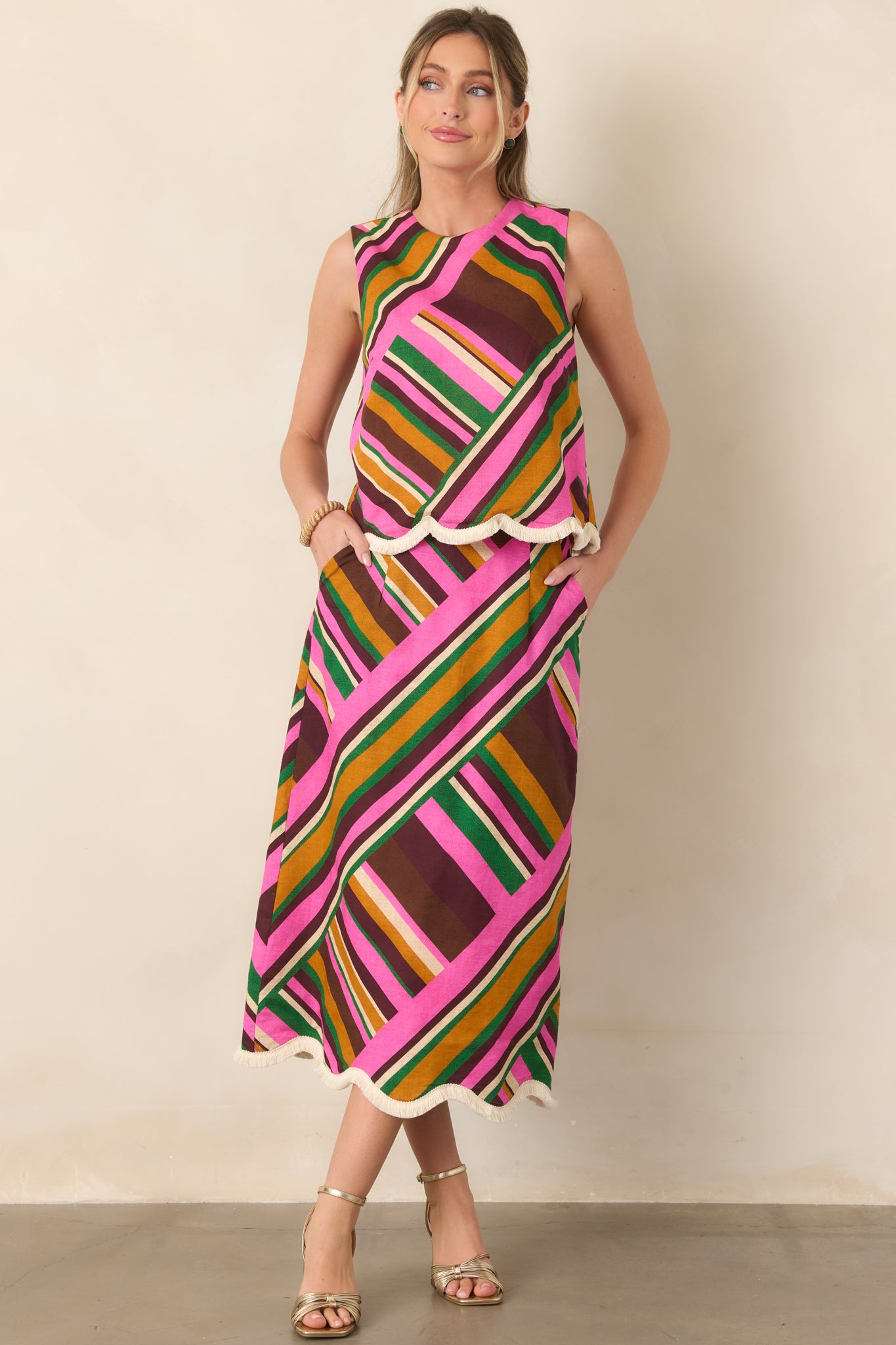 Eye-catching midi skirt featuring colorful geometric stripes, a smooth high-rise waist, flowing silhouette, and playful scalloped fringe edging.