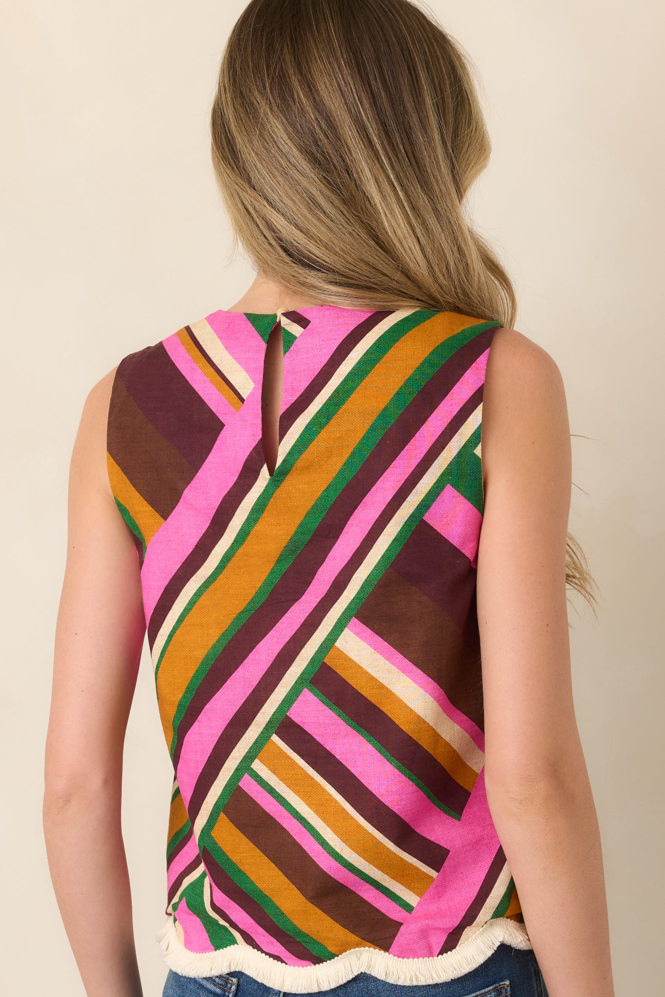 Rear view of the pink geometric striped sleeveless top, featuring a relaxed shape and keyhole detail beneath the round neckline.