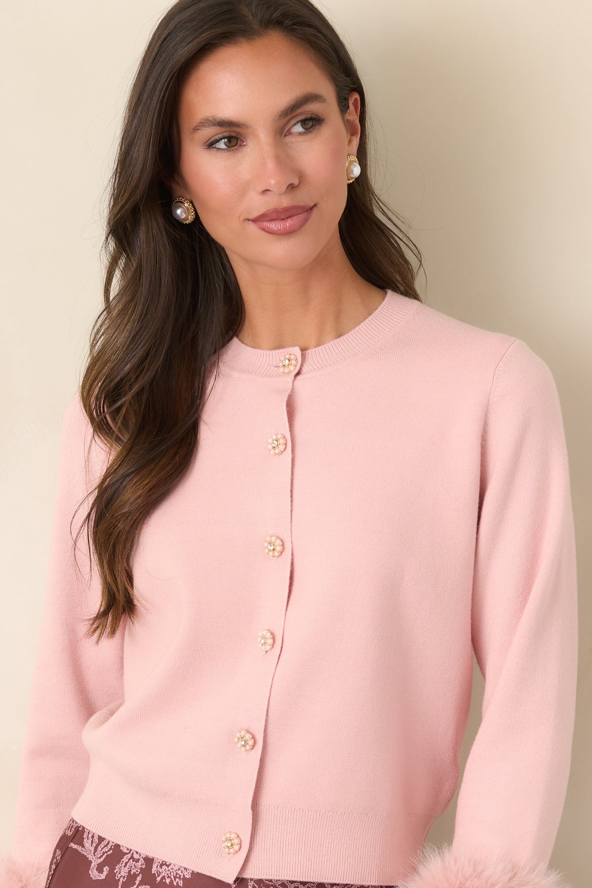 Pink knit cardigan featuring removable faux fur cuffs attached with decorative buttons.