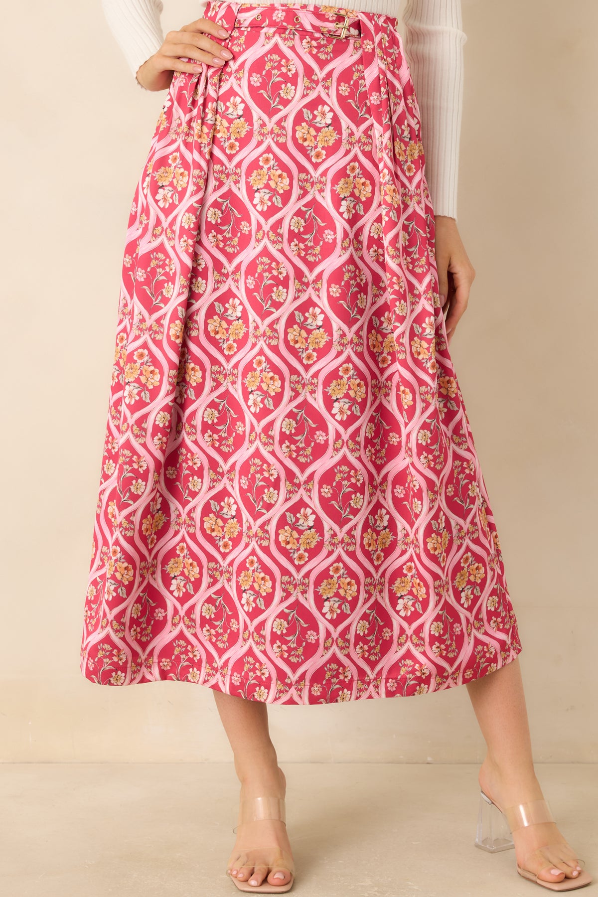 Pink midi skirt with deep front pleats that open into a gently flared shape.