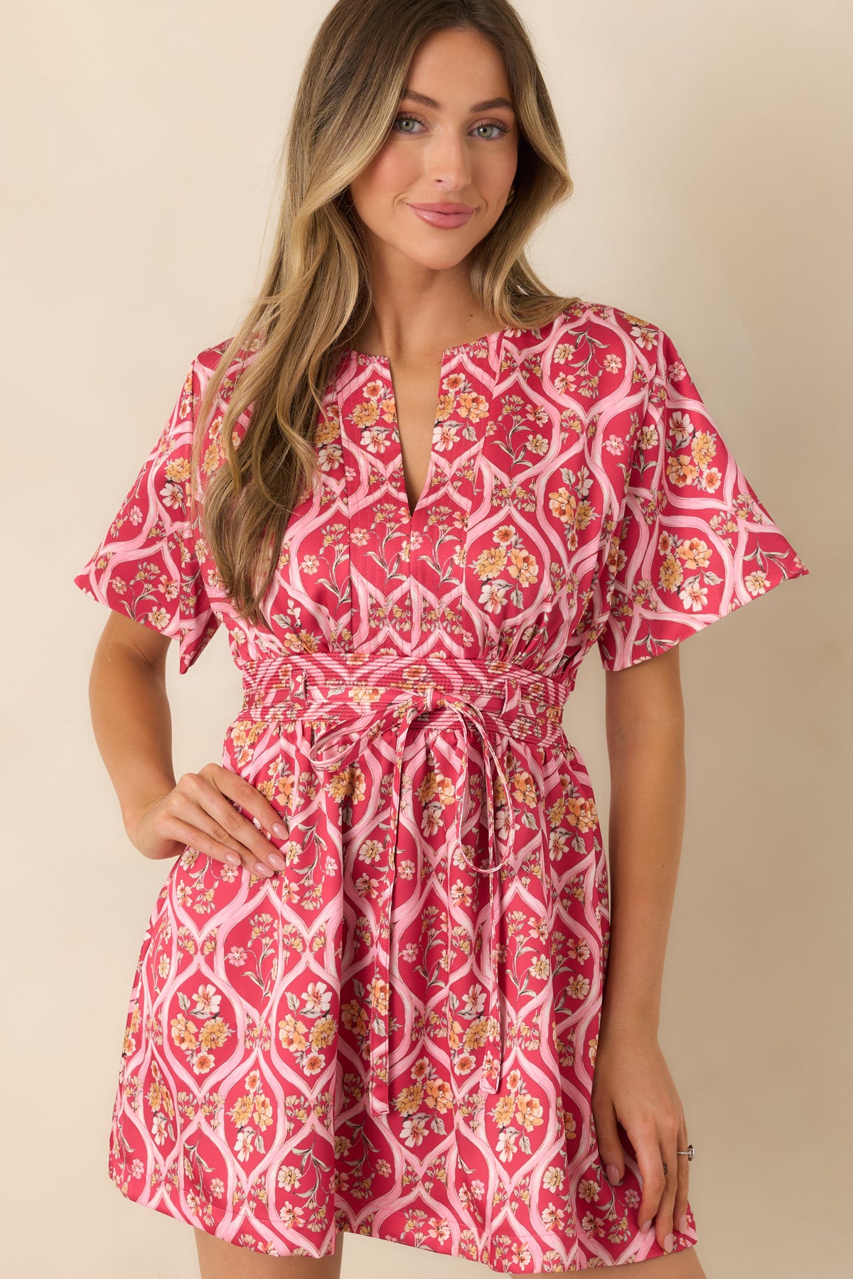 Pink mini dress featuring a fitted waist and a lined skirt that flares gently toward the hem.