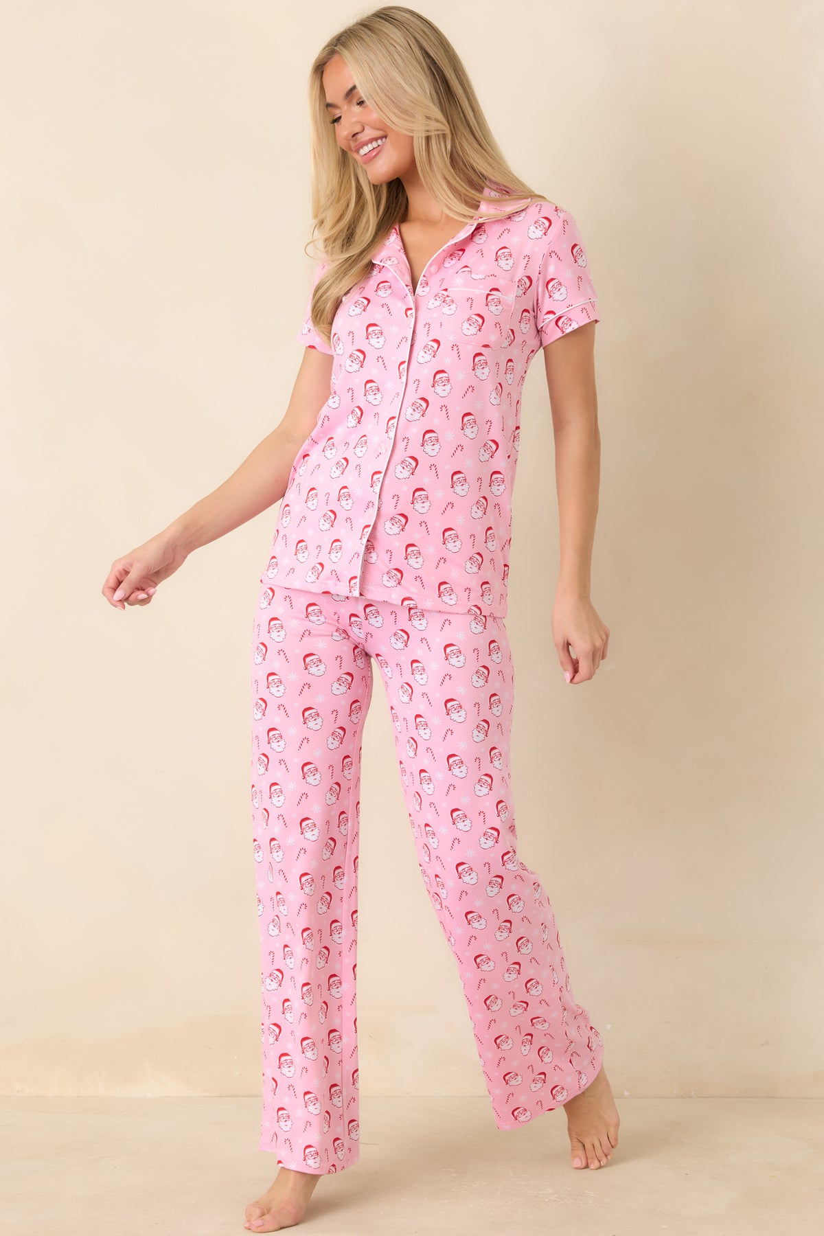 Light pink holiday pajama pants showcase a festive Santa pattern and an adjustable drawstring waistband.