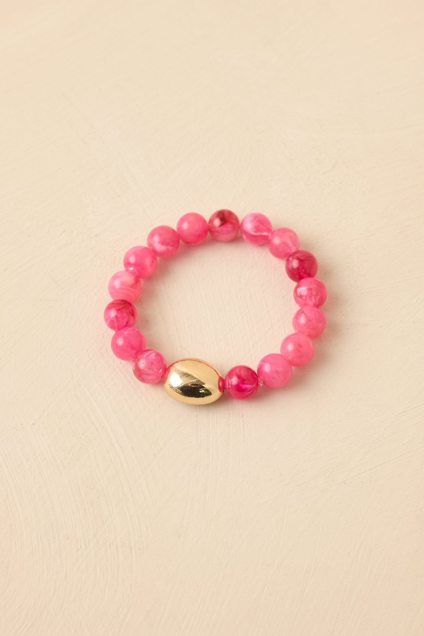 Stretch bracelet with vibrant pink beads and a gold-tone accent bead shown from an alternate angle.