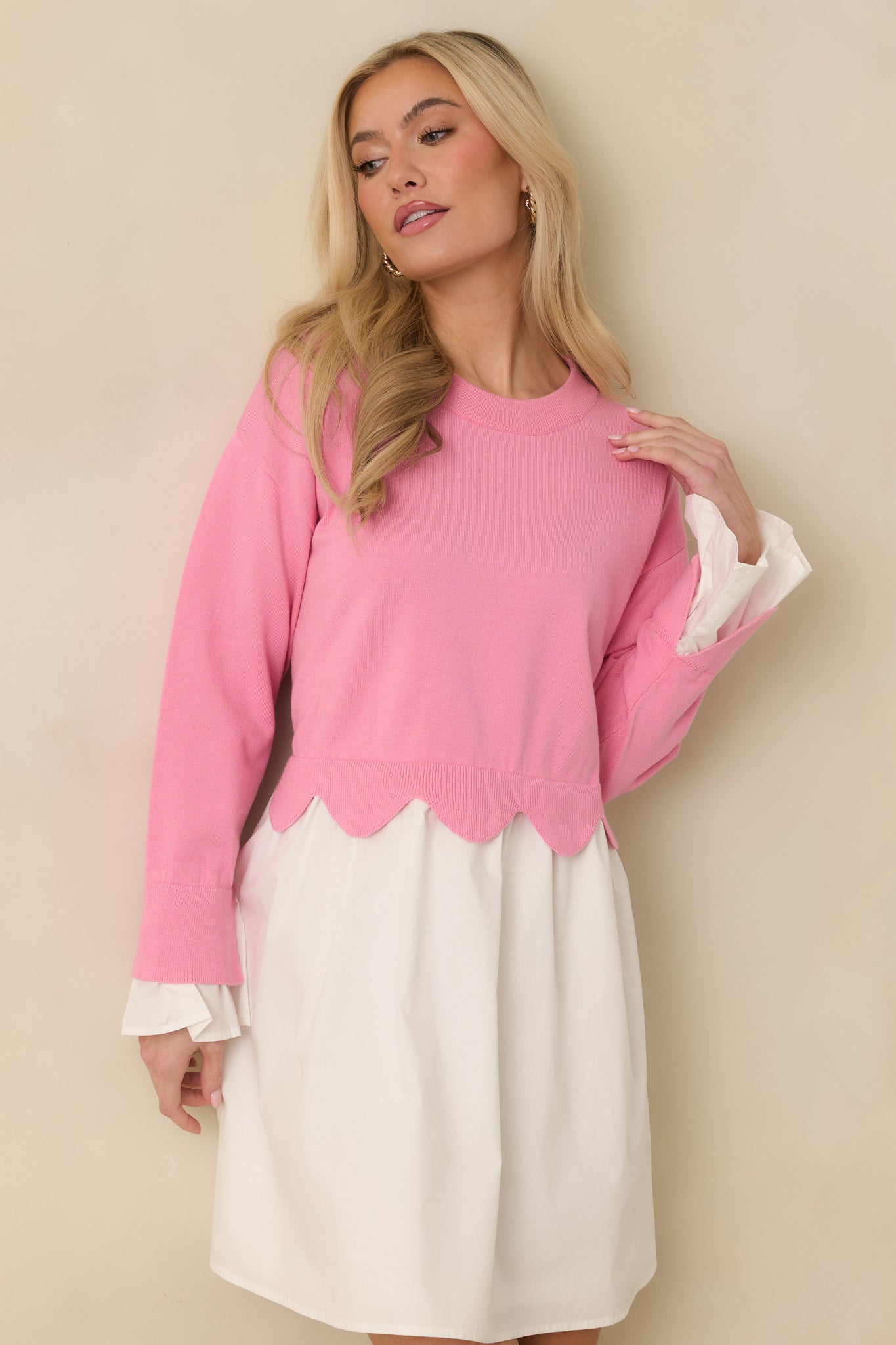 Cropped front-focused shot highlighting the long sleeves and knit texture of the pink and white mini dress.