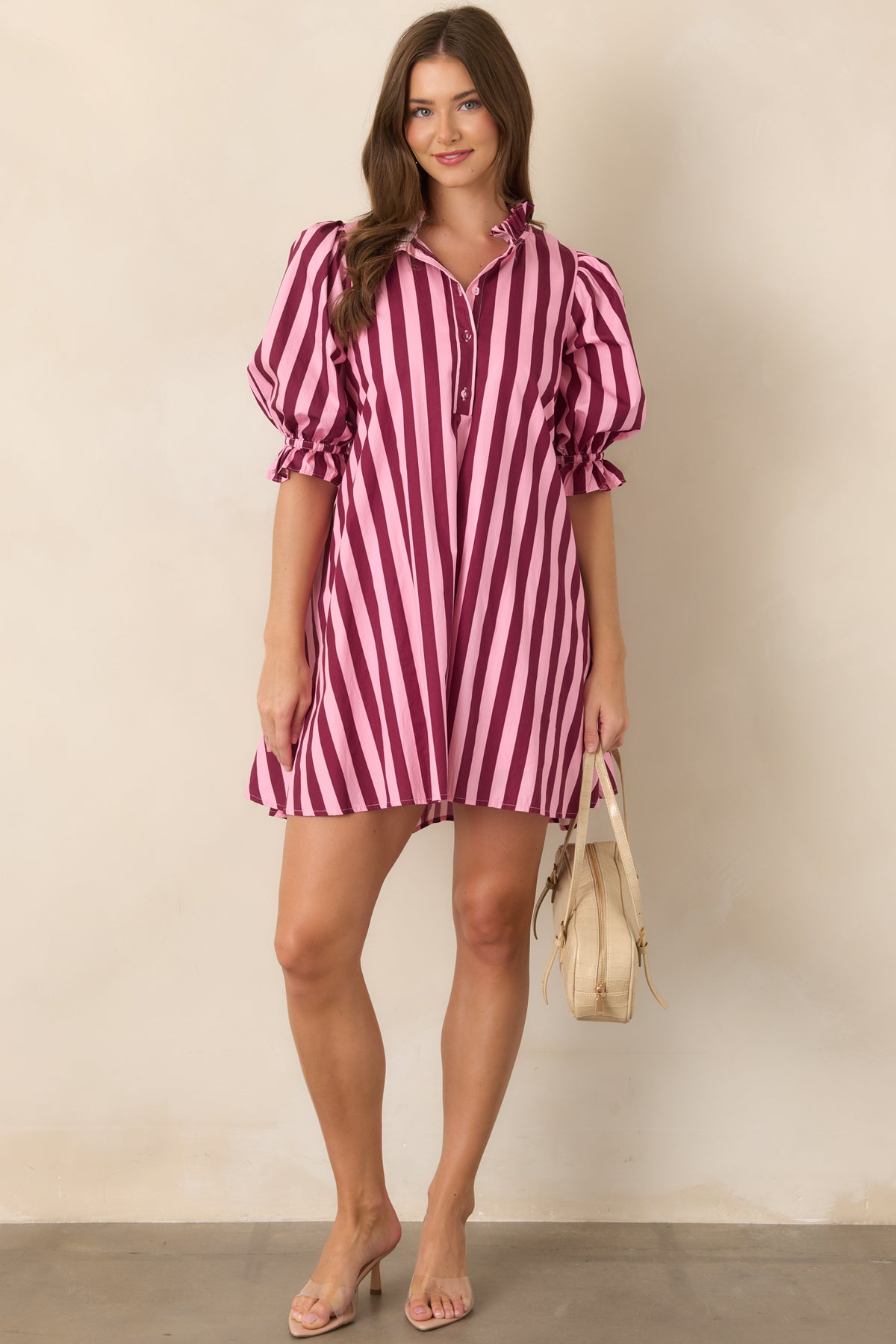 Pink and wine striped shift mini dress showcasing a softly structured cotton fabric, voluminous sleeves, ruffle-trimmed cuffs, and a subtle drawstring waist.