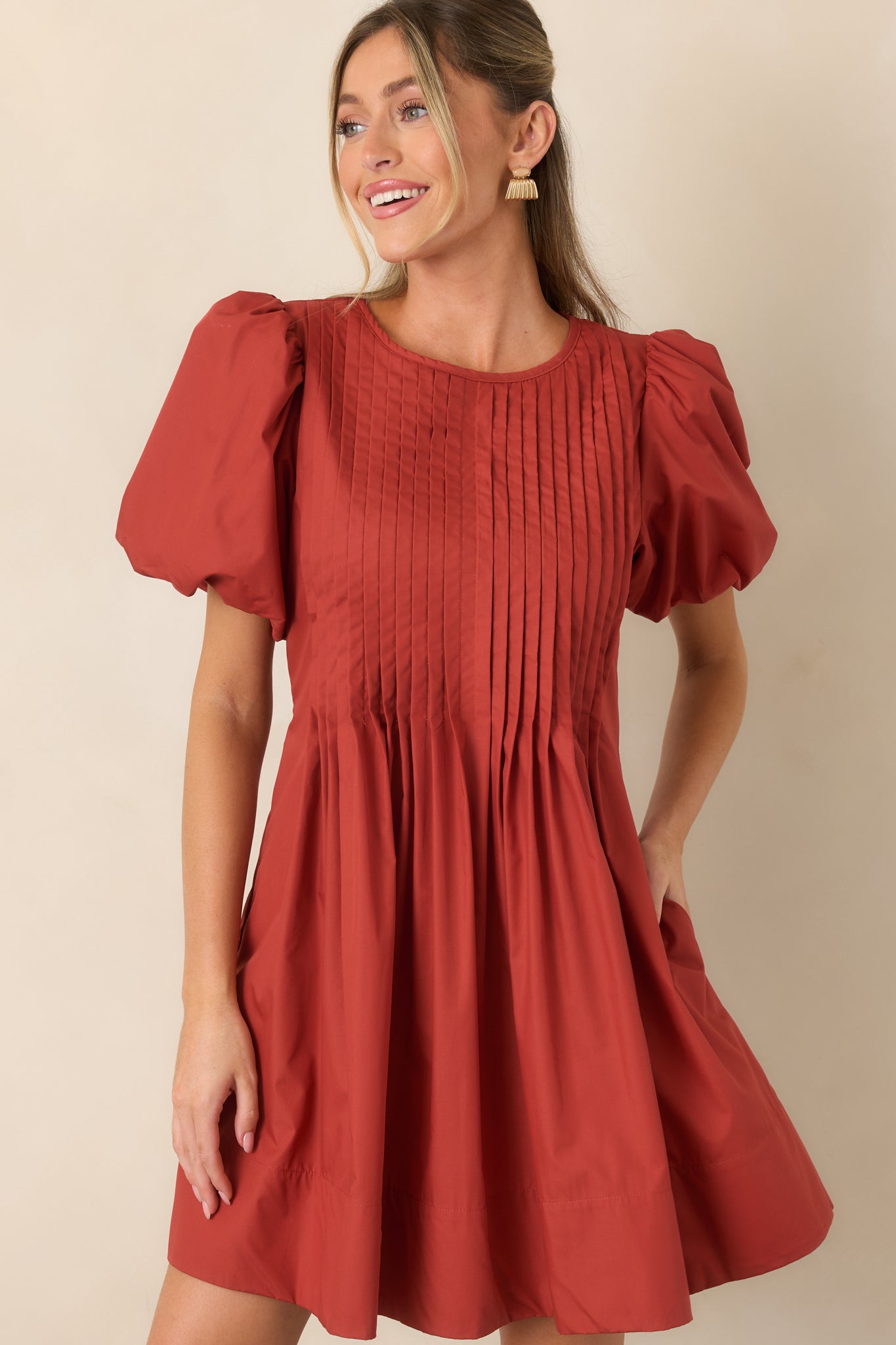 Detailed pintucks add texture across the bodice, complemented by voluminous short puff sleeves and a smooth finish.