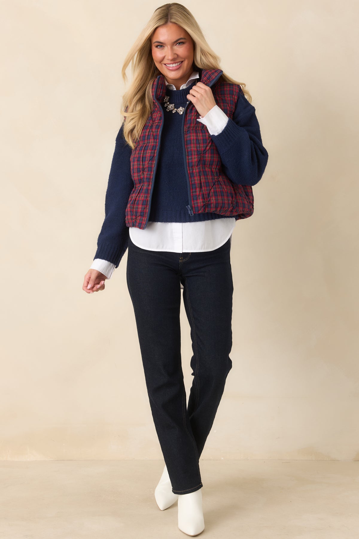 Plaid quilted vest with a stand collar, navy front zipper, and rounded stitching throughout.