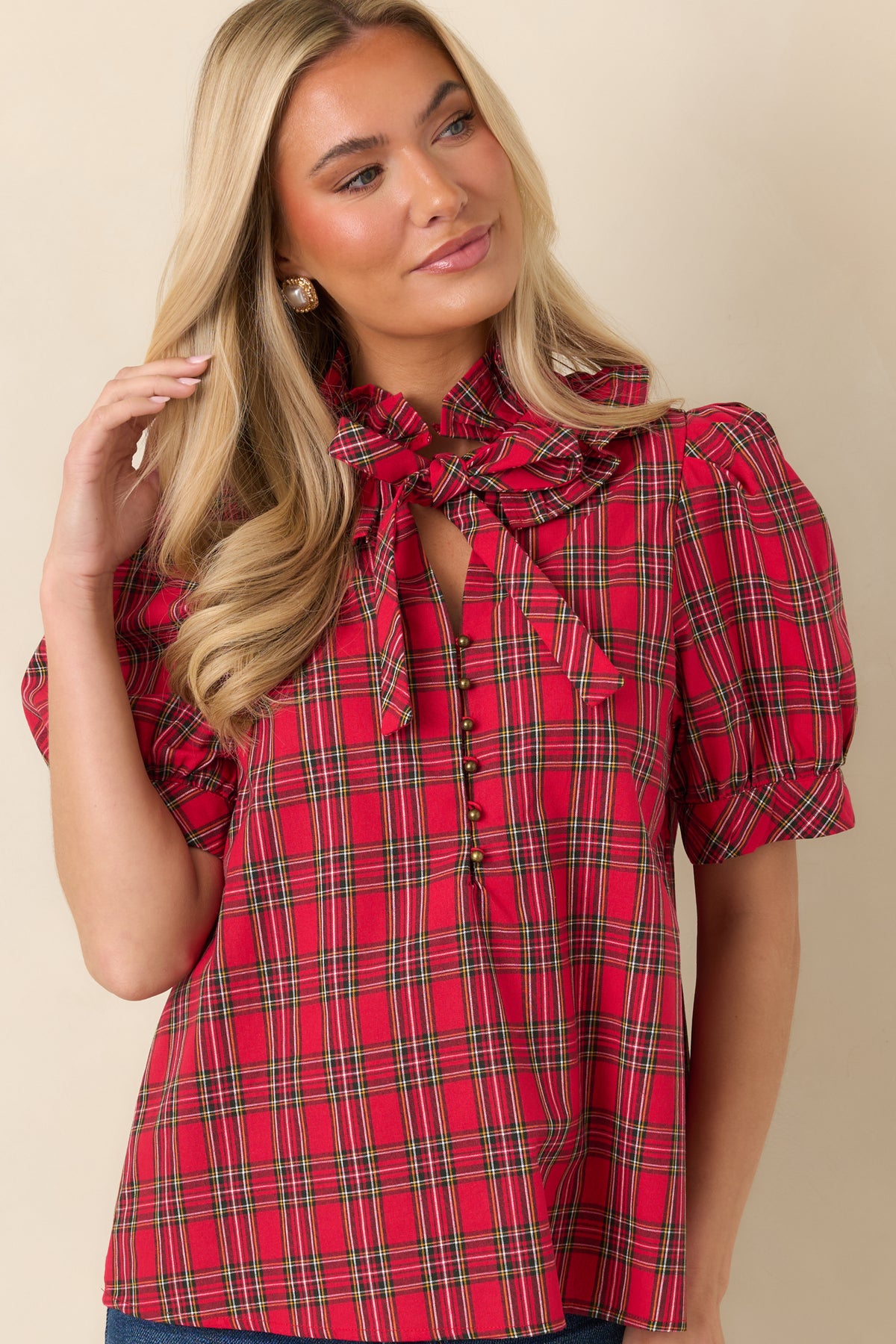 Classic plaid top featuring small round buttons beneath the neckline opening and a decorative bow tie.