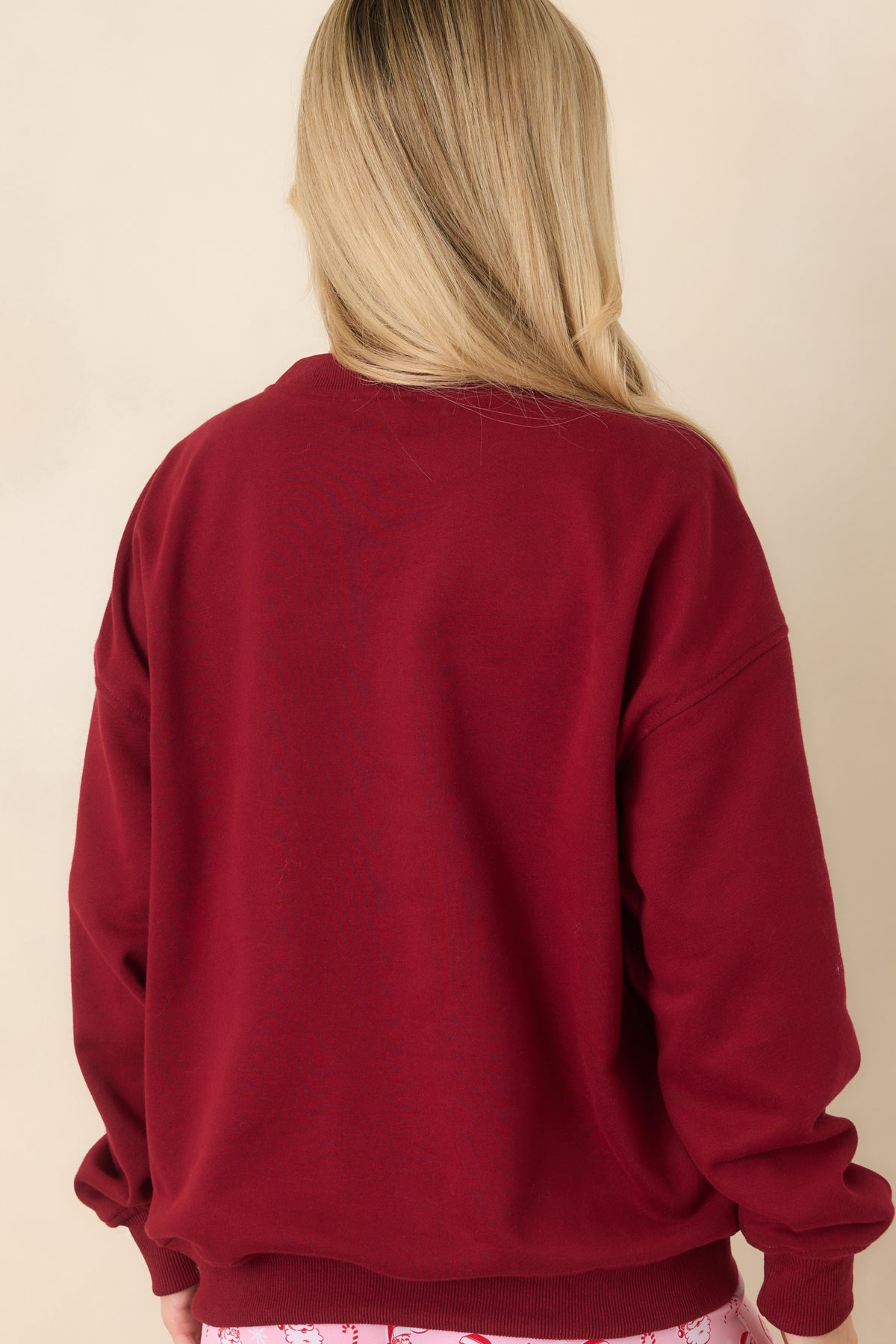 Back of the relaxed pullover top featuring a plain fabric design with long sleeves, ribbed cuffs, and a matching ribbed hem.