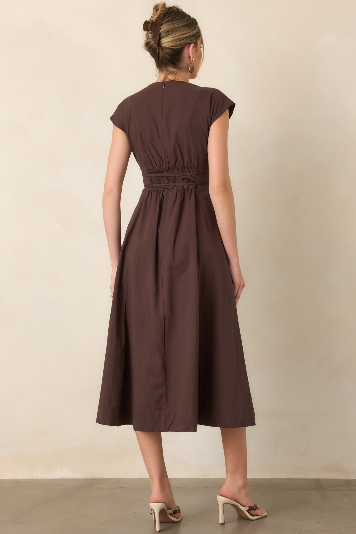Rear view of the midi dress, highlighting its softly pleated fabric, cap sleeves, defined waist, and gently gathered skirt.