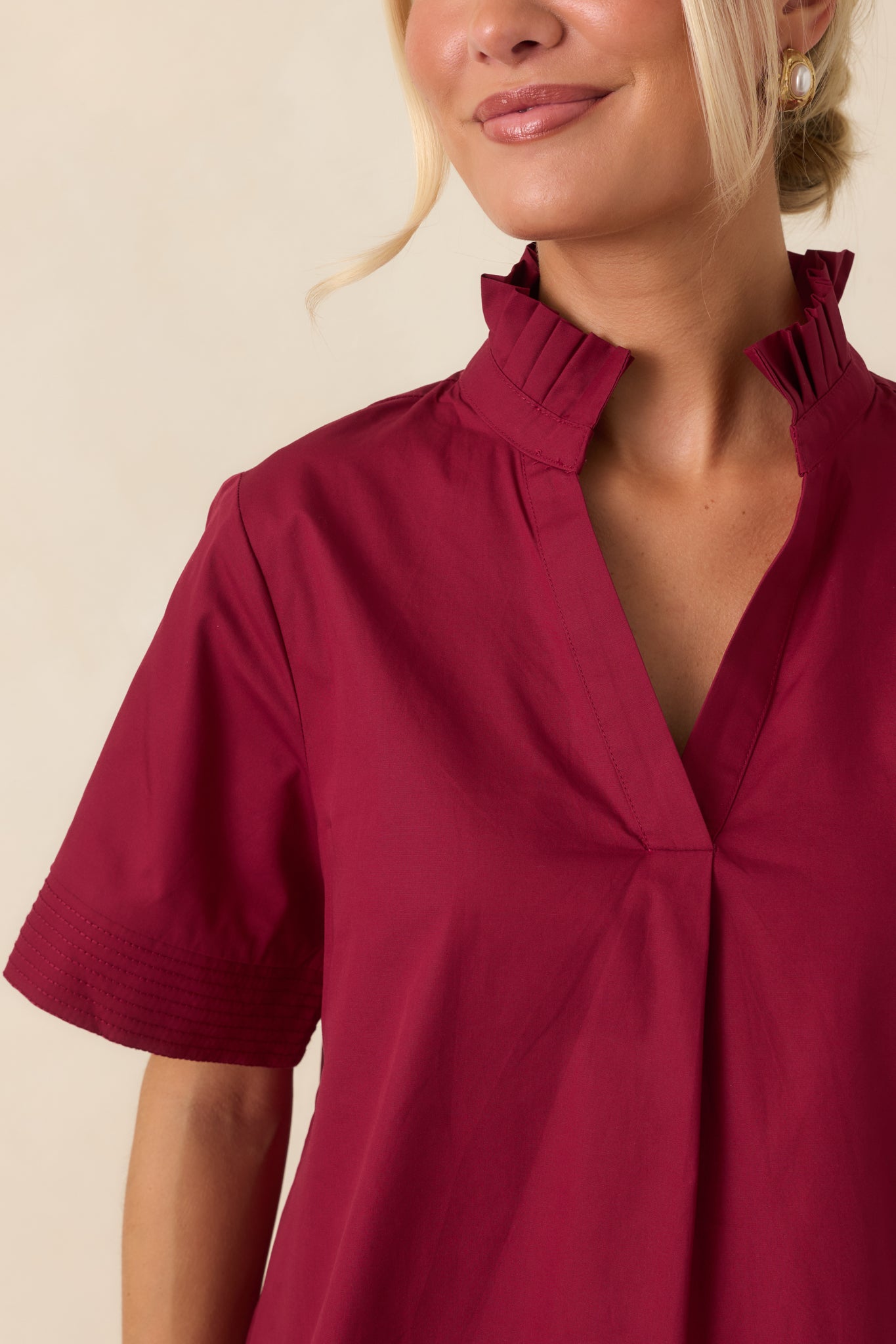 Close-up of the top highlighting the pleated ruffle collar, split neckline, and delicate stitched detailing.