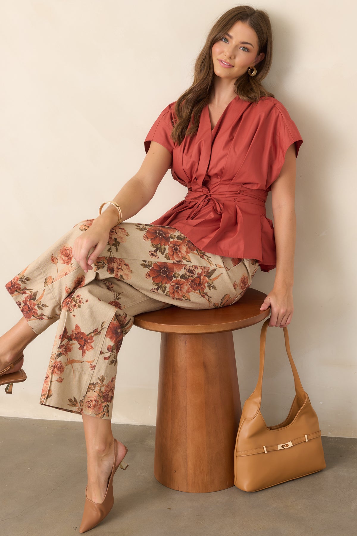 V-neck top showcasing structured pleating across the bodice, dramatic short sleeves, adjustable waist ties, and a flared hem.