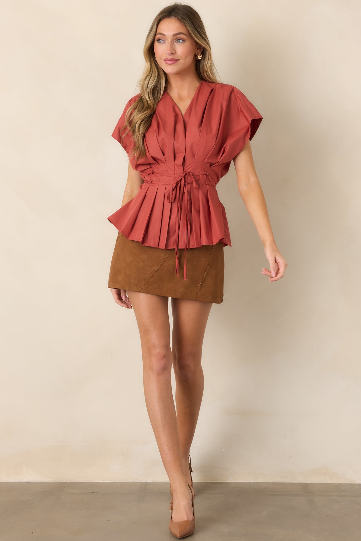 Pleated top with a flattering V-neckline, movement-filled short sleeves, a tie waist, and a softly flared peplum hem.
