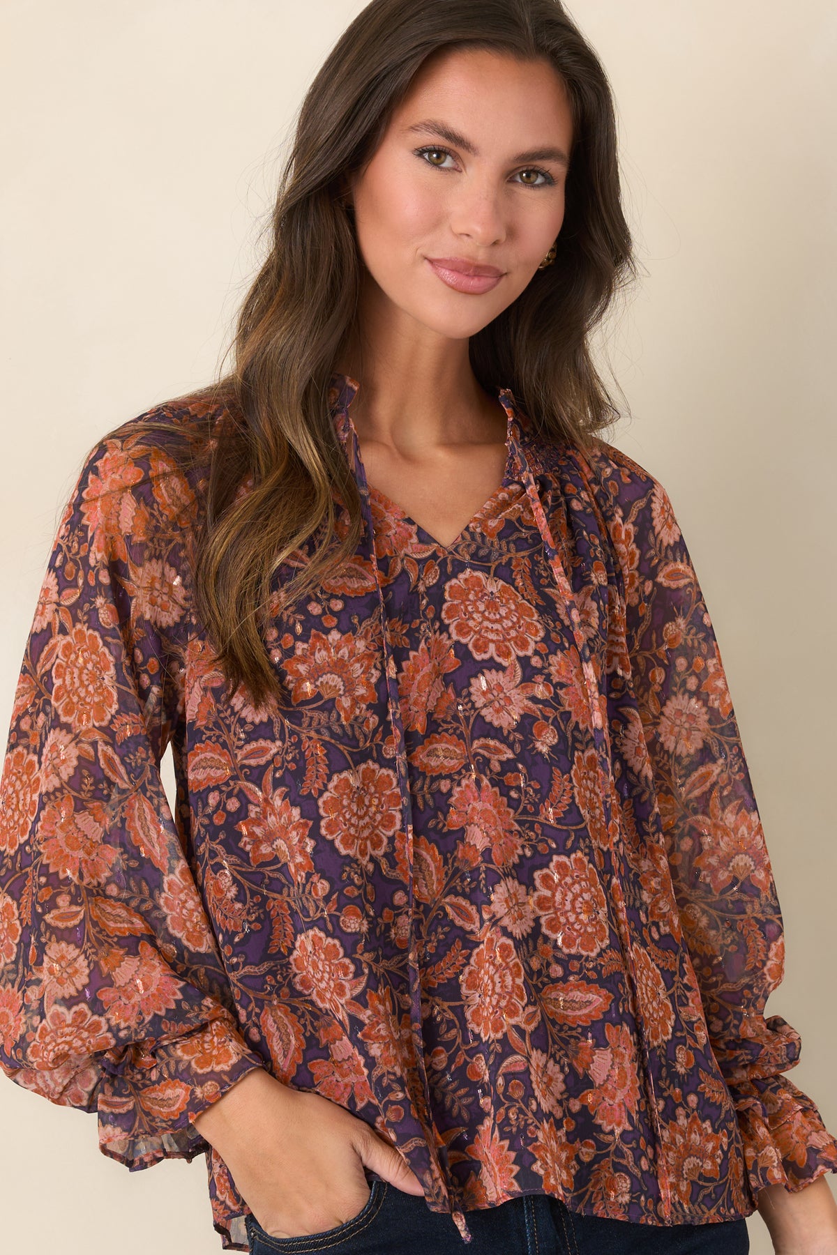 Plum and coral floral top with a flowing neckline, delicate front ties, and romantic ruffle details.