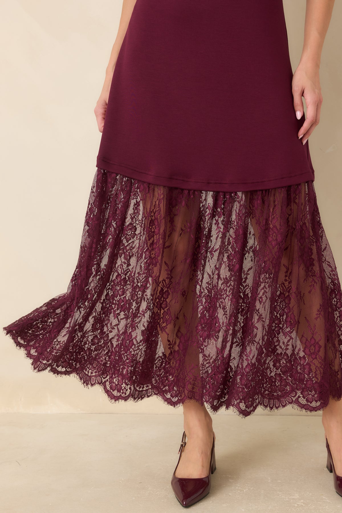 Close-up of the plum dress highlights the smooth knit fabric, intricate floral lace pattern, and scalloped edge.