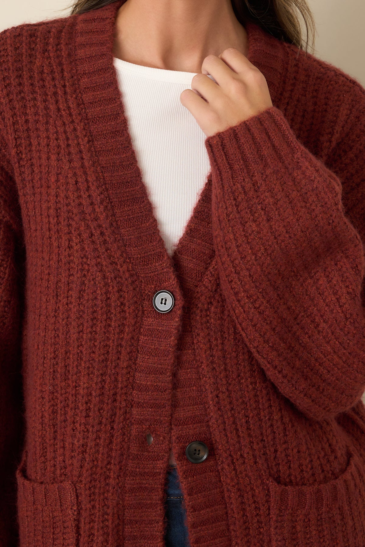 Close-up of the plush knit texture, dark button front, and wide ribbed trim along the V-neckline.