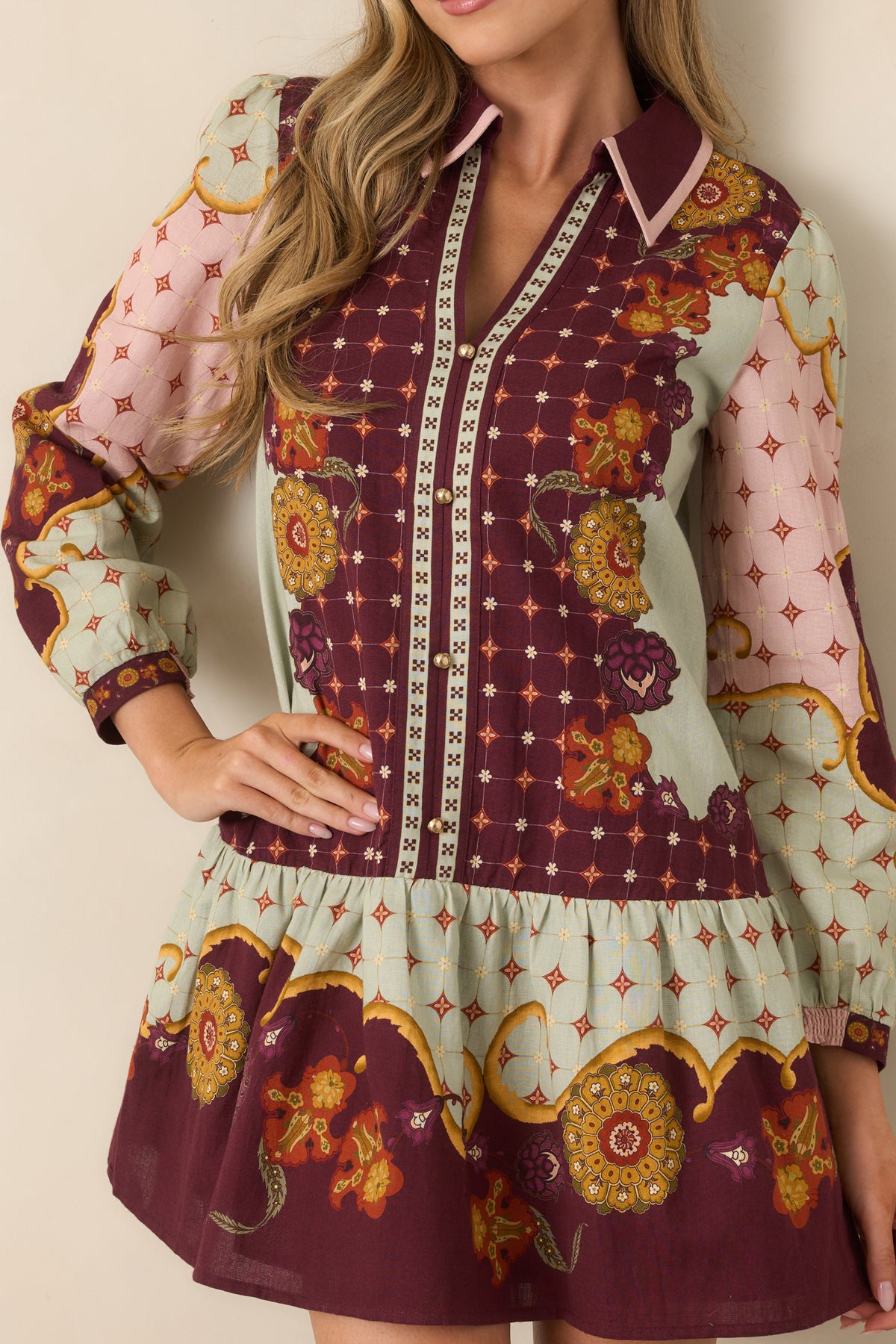Close view of the pointed collar, pink neckline trim, ornate print, and gold-tone buttons.