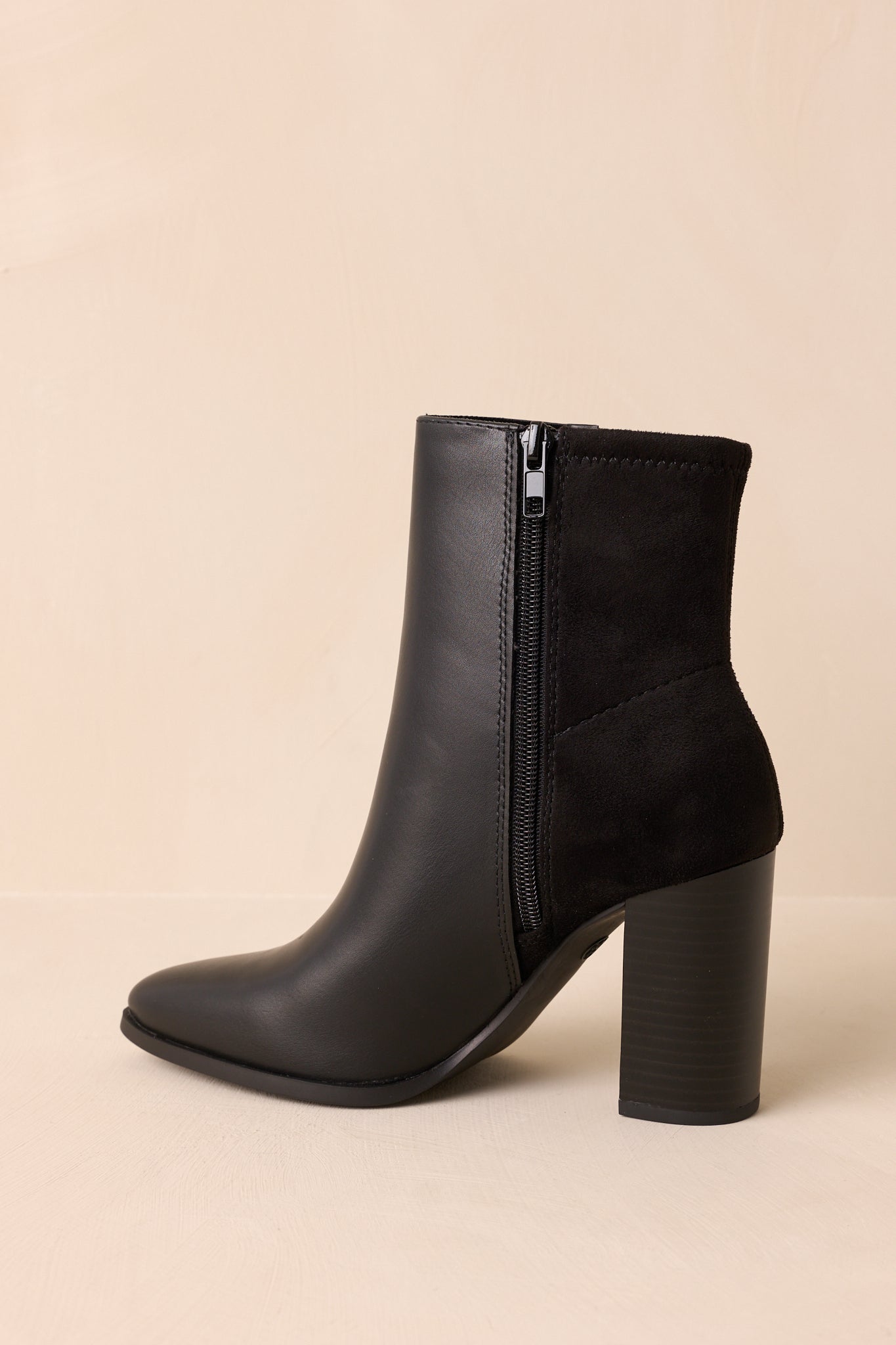 Pointed toe black ankle boots featuring smooth faux leather construction, stacked heel, cushioned insole, and refined mixed-material design.