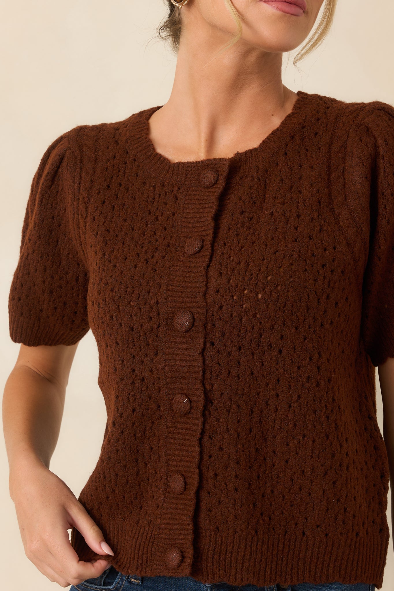 Close-up of the cardigan showcasing the intricate pointelle knit, covered buttons, and soft textured fabric.