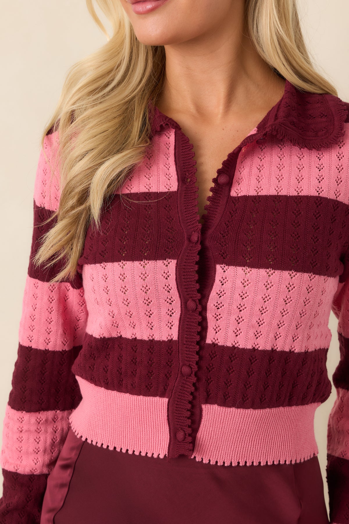 Close-up of the pointelle knit openings, alternating wine and bright pink bands, and scalloped edging.