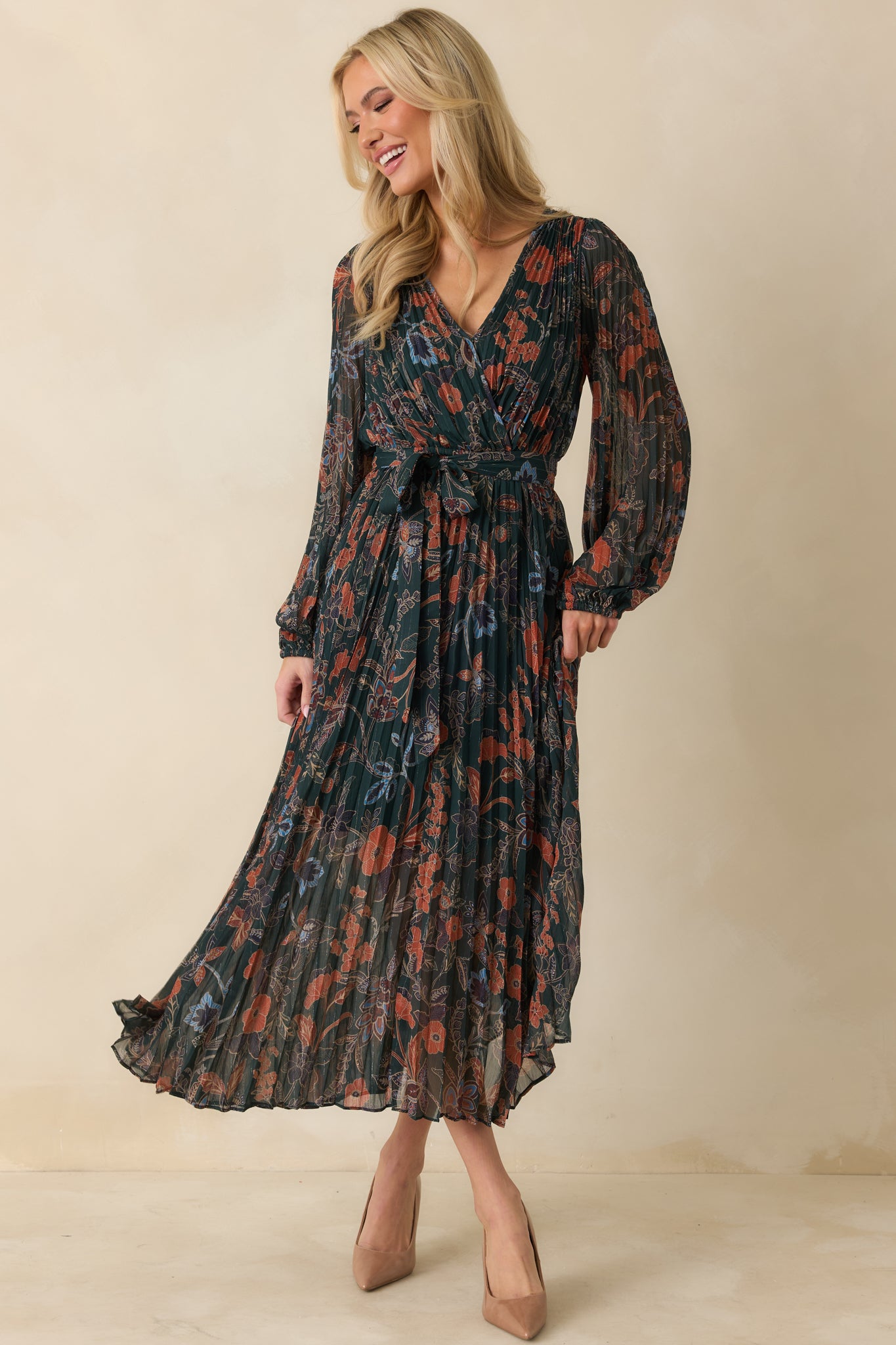 Posed front view showing the soft drape of the dress and flowing pleated hemline.