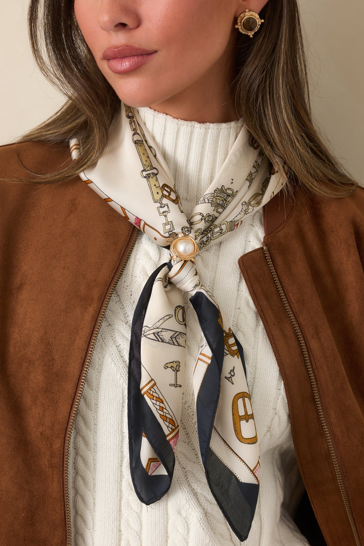 Printed neck scarf featuring a luminous pearl accent in a round gold-tone setting with a decorative textured border.