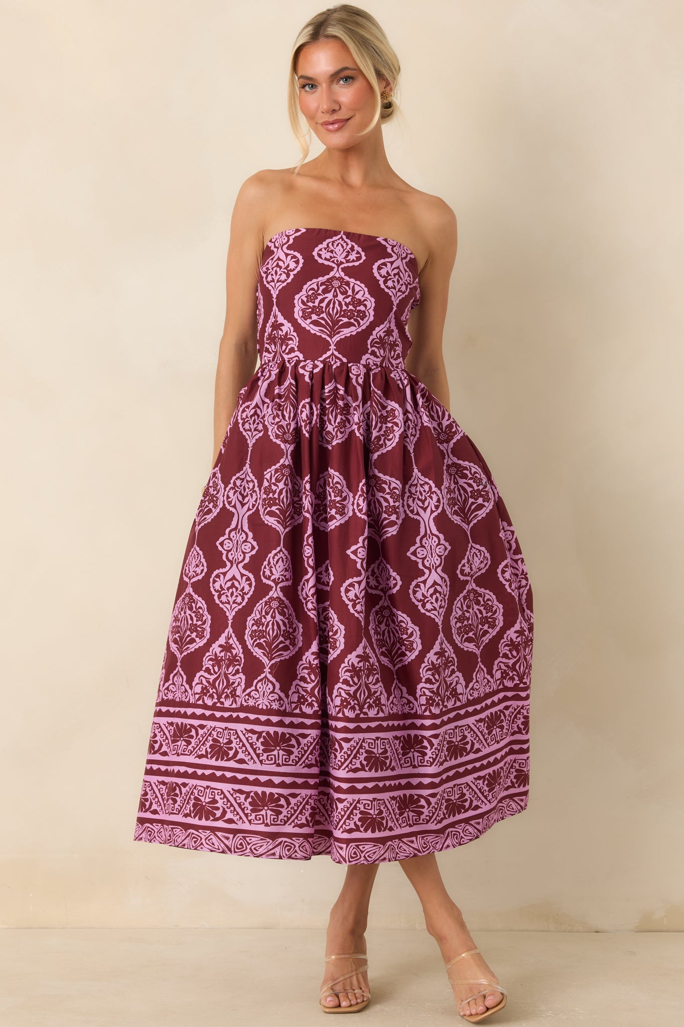 Printed midi dress showcasing a structured strapless bodice, floral-inspired medallion design, border trim, and flowing skirt.