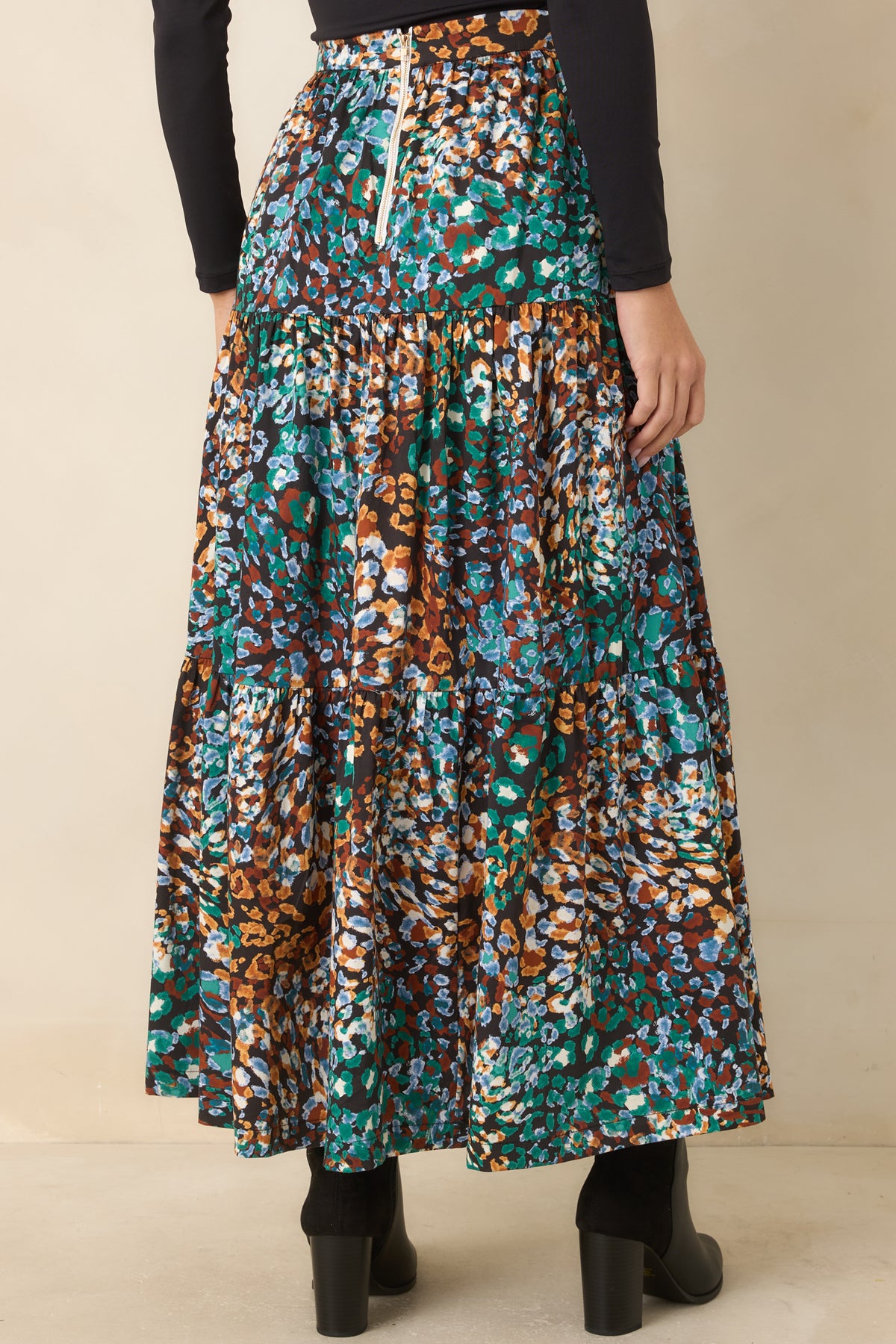 Rear of the printed tiered skirt showing the high-rise waistband, gold back zipper, and flowing layers.