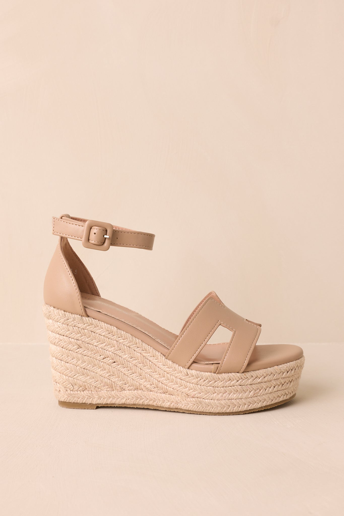A profile view showcasing the entire wedge heel, the tan ankle strap with a buckle, and the tan faux leather H strap across the toe.