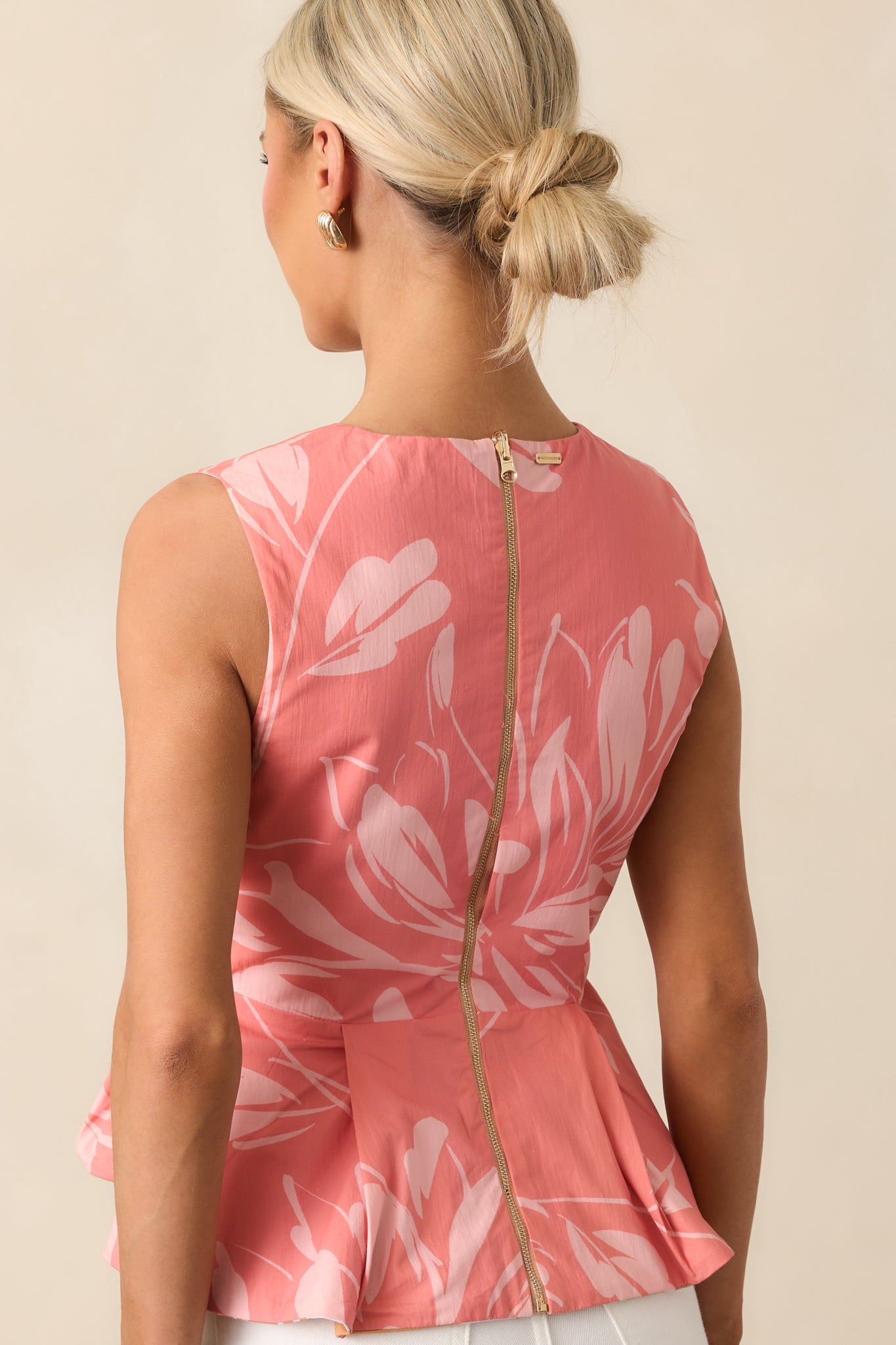 Rear view of the rose floral top showing gold back zipper closure and sleeveless peplum shape.
