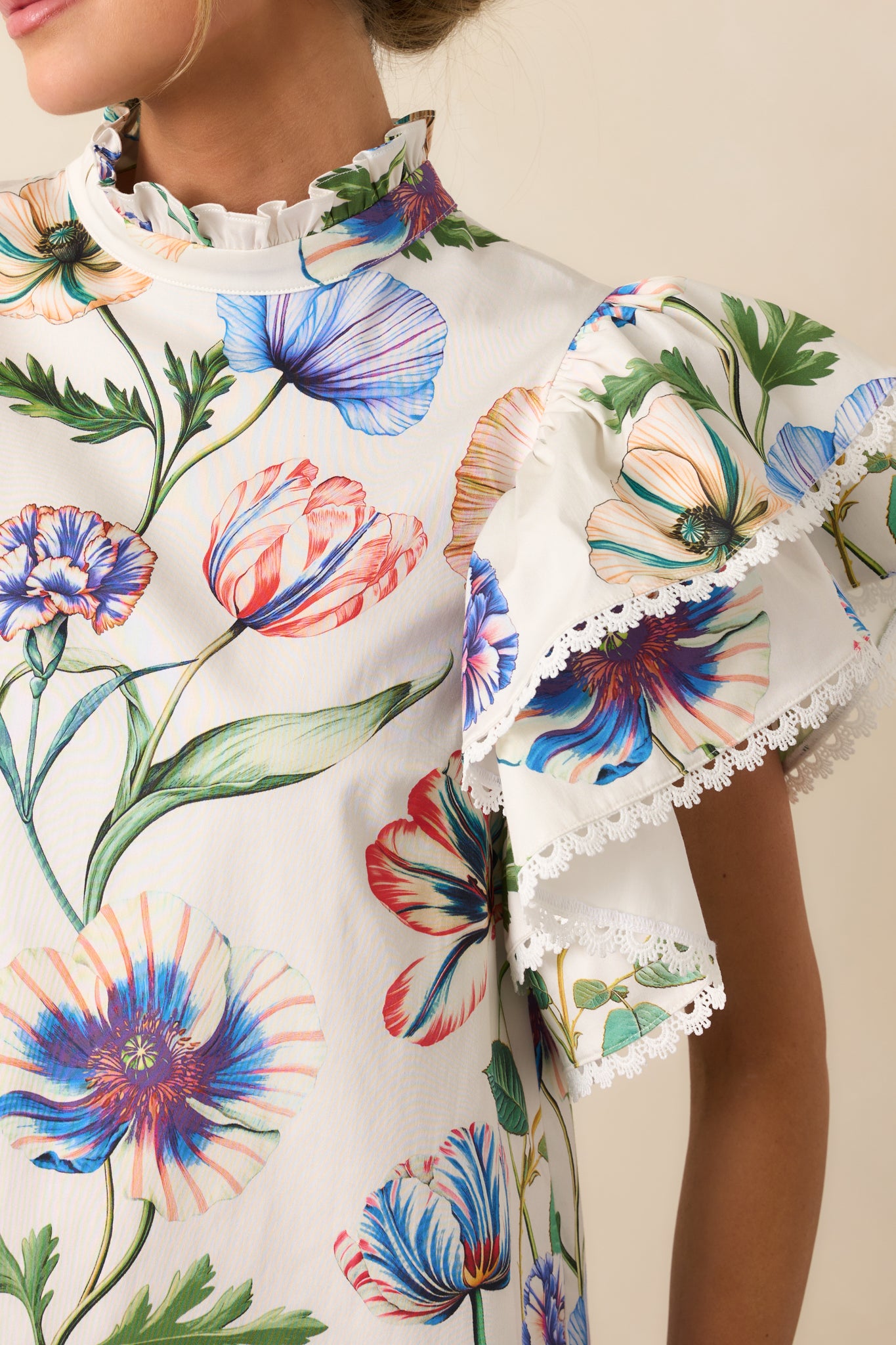 Detailed view of the multicolor floral print, ruffle mock neckline, and ivory eyelet trim.