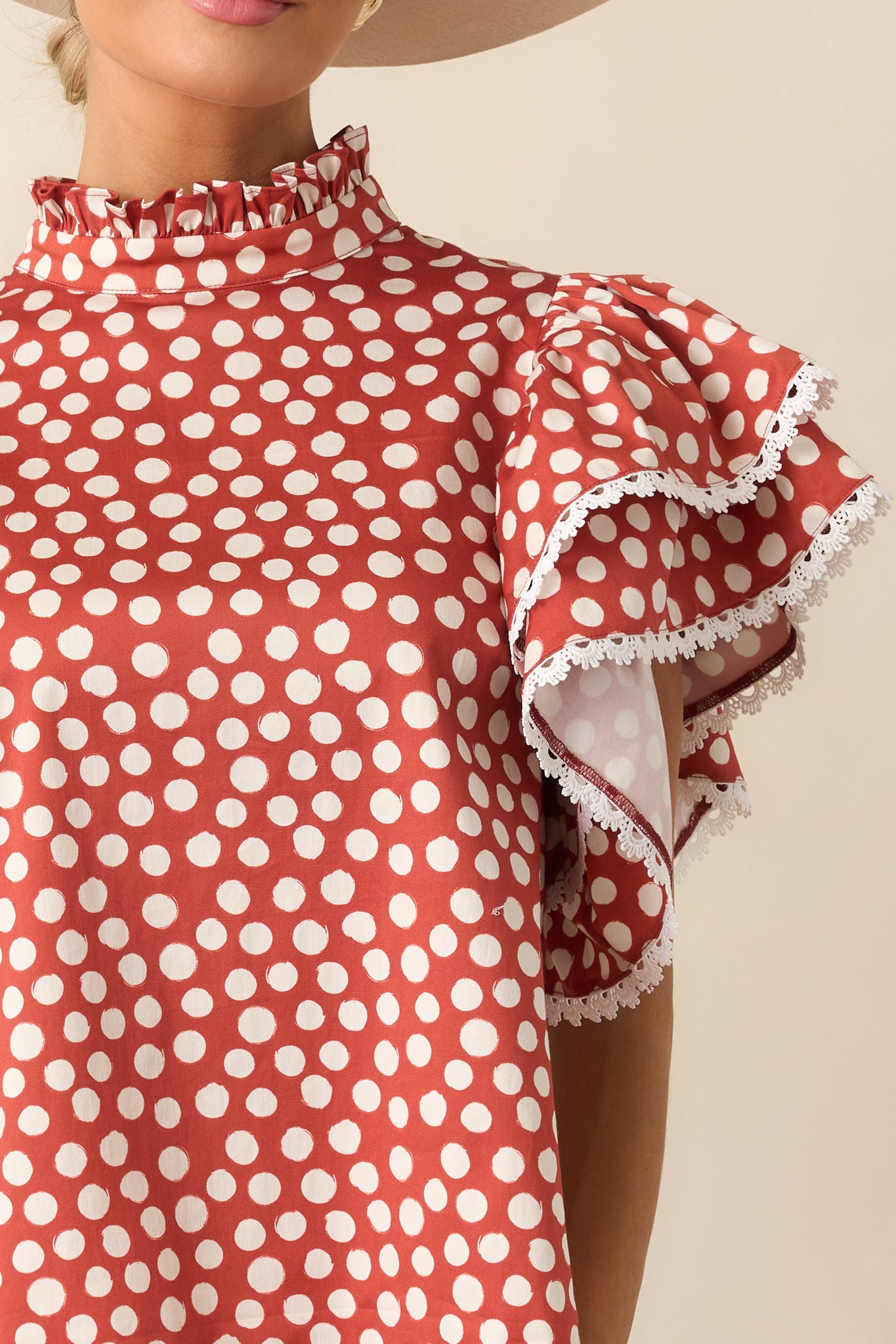 Detailed look at the brick red and white polka dot fabric, ruffle neckline, and ivory eyelet trim.