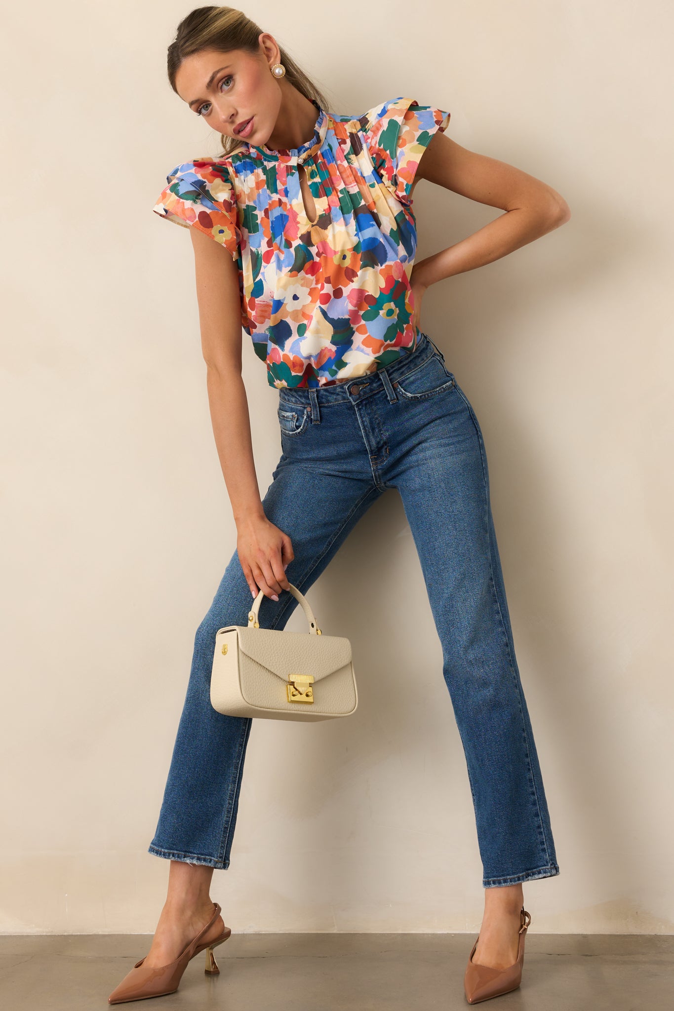 Orange multicolor floral top with a ruffle mock neckline and short flutter sleeves.