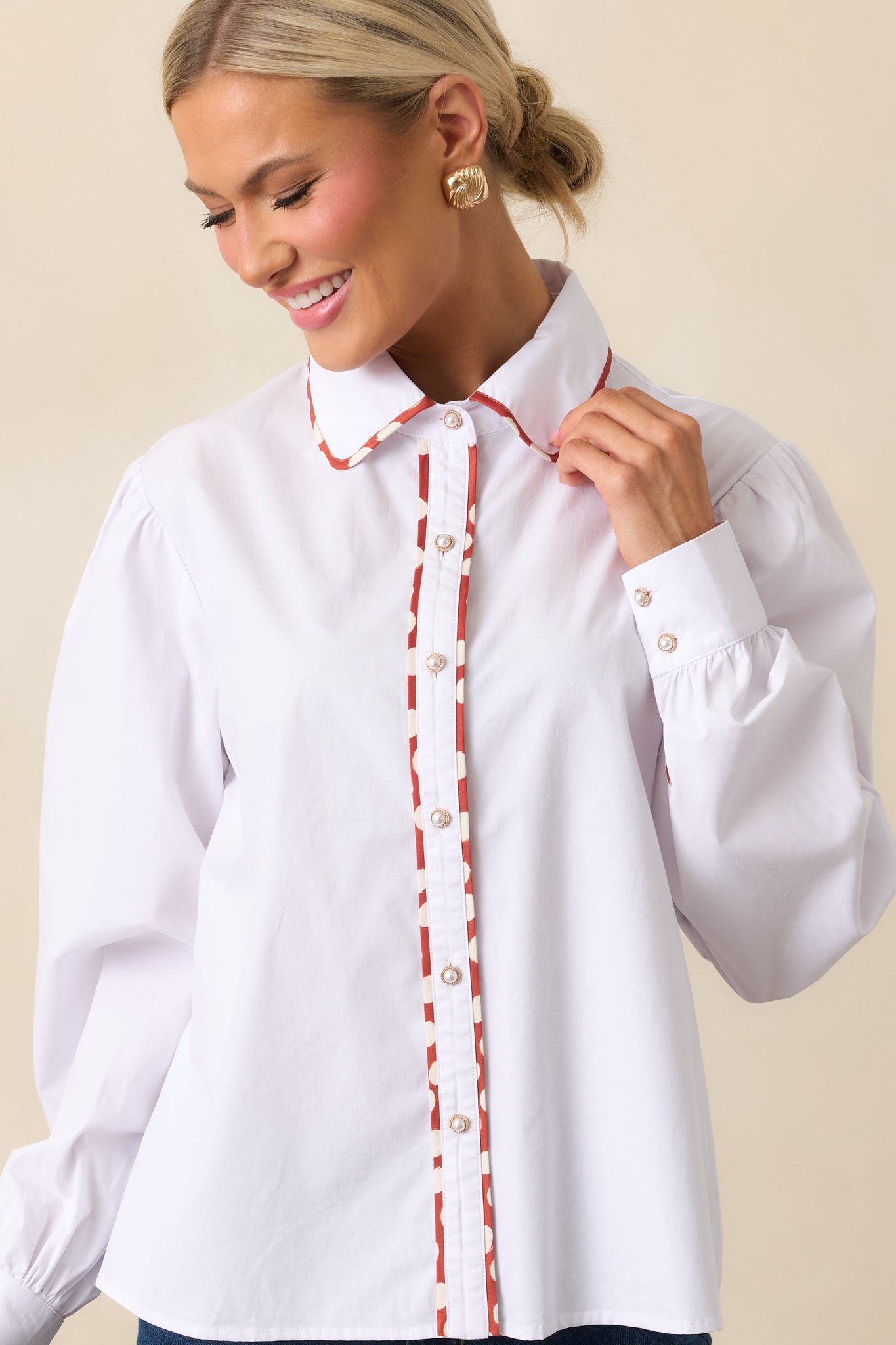 White top showing long sleeves and ivory faux pearl button cuffs