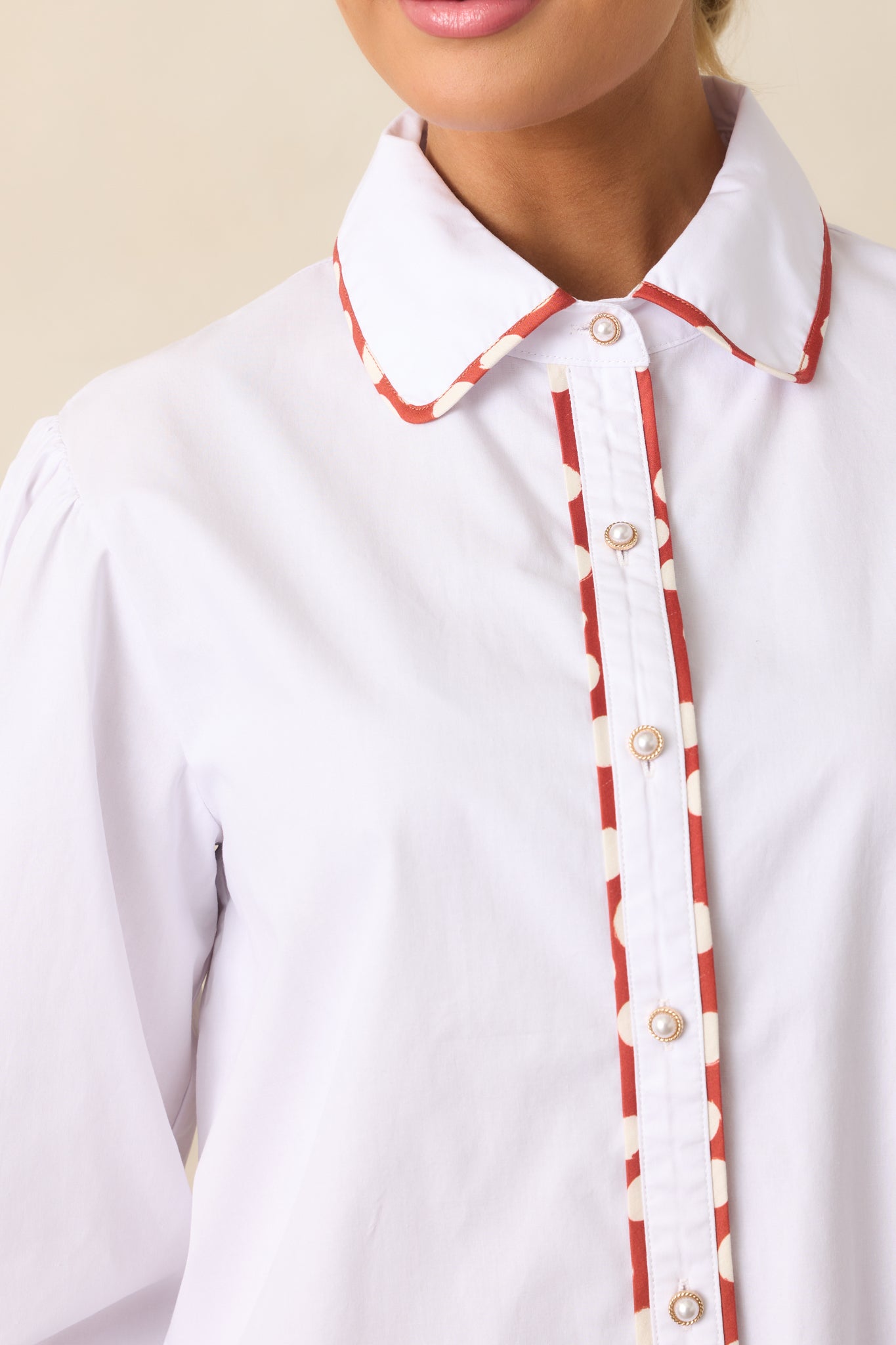 Detailed look at the rust red and ivory polka dot contrast trim and collared neckline.