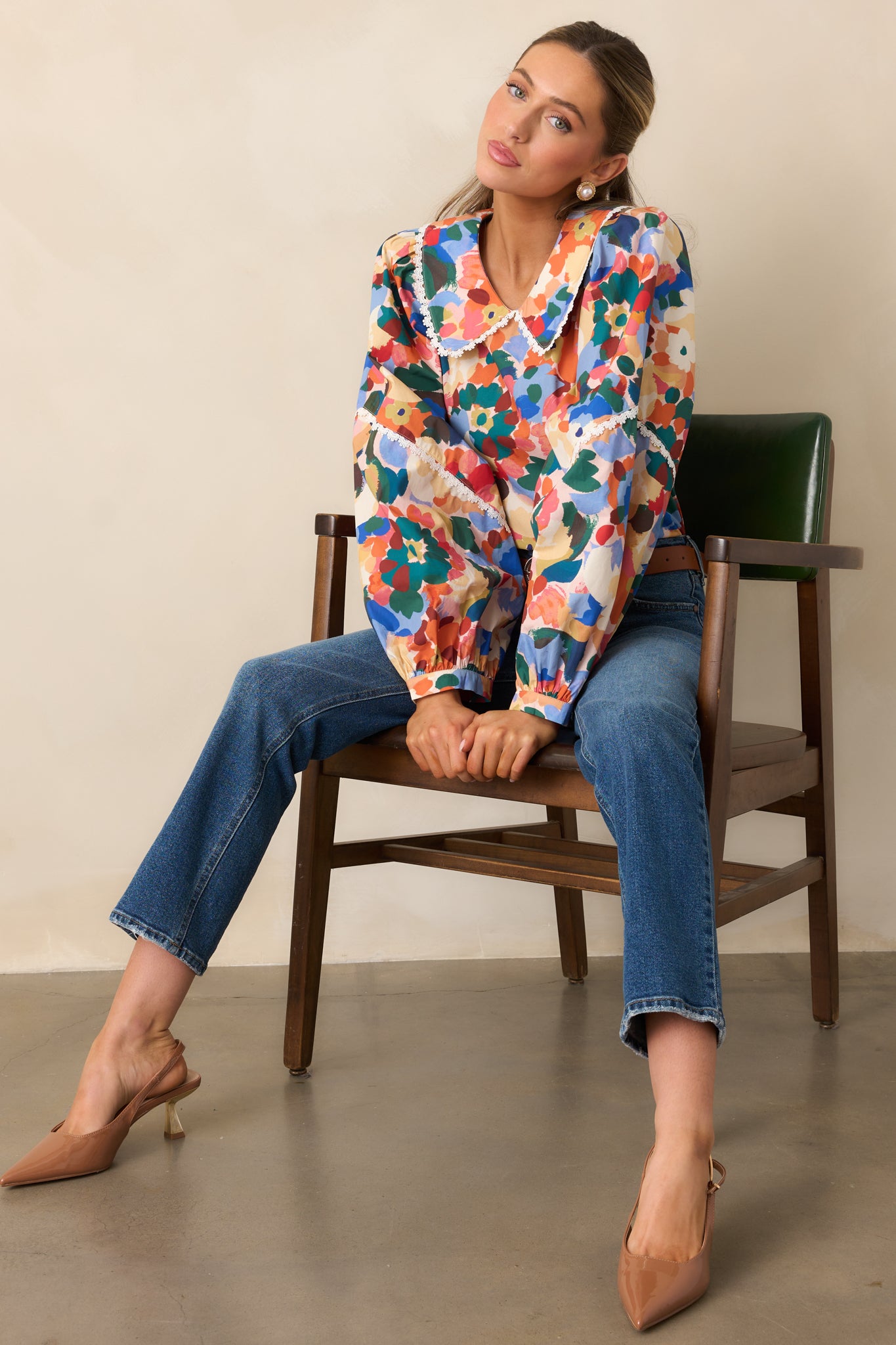 Orange multicolor floral top with a peter pan collar and long puff sleeves with button cuffs.