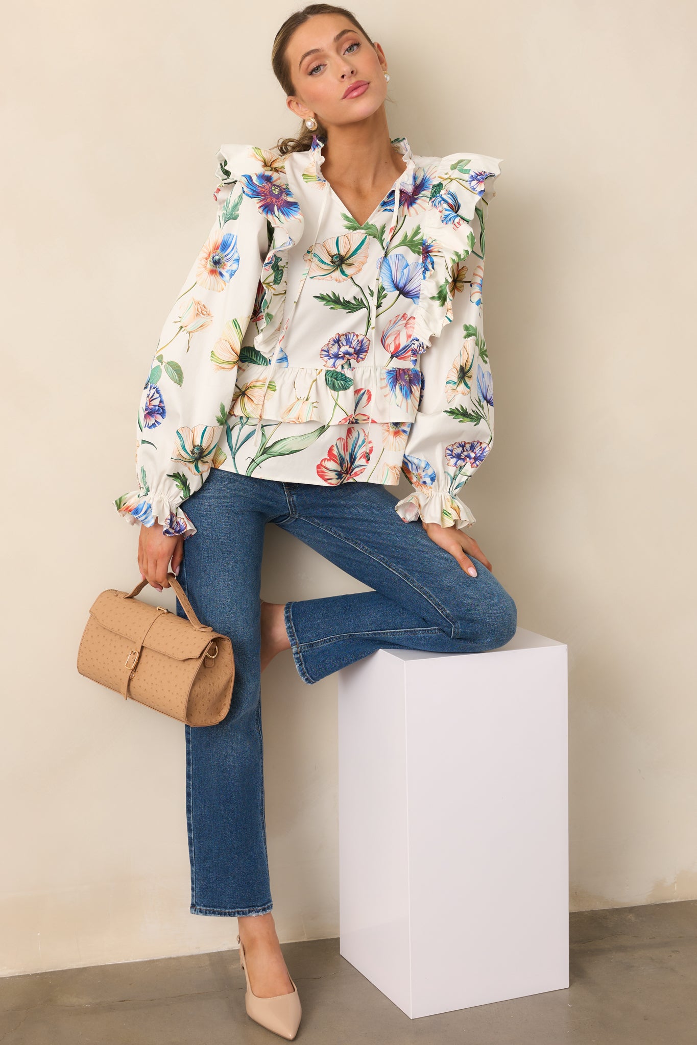 Ivory top with long sleeves, ruffle accents, and vibrant multicolor floral design.