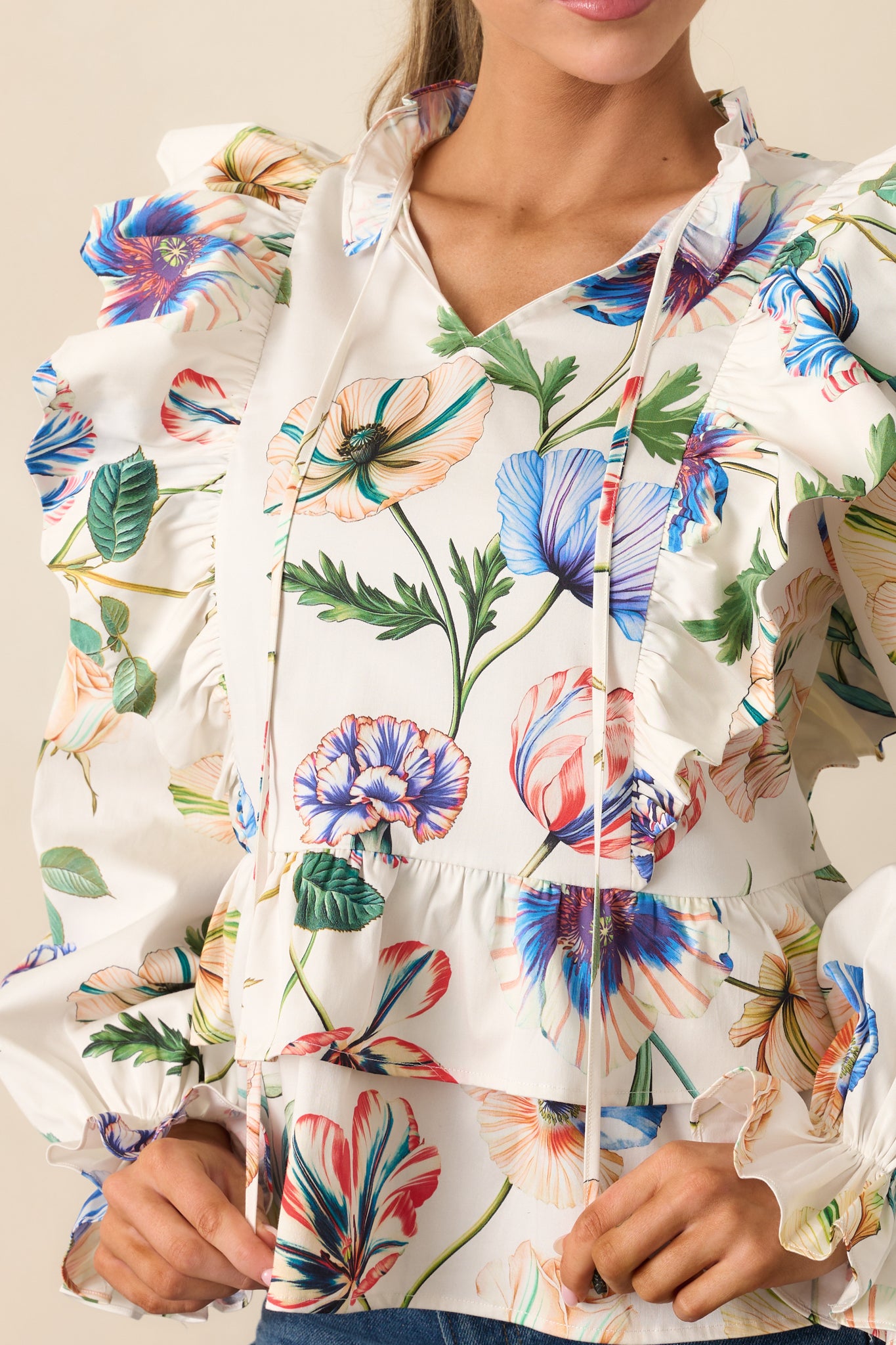 Detailed view of the multicolor floral print, ruffle paneling, and tassel tie neckline.