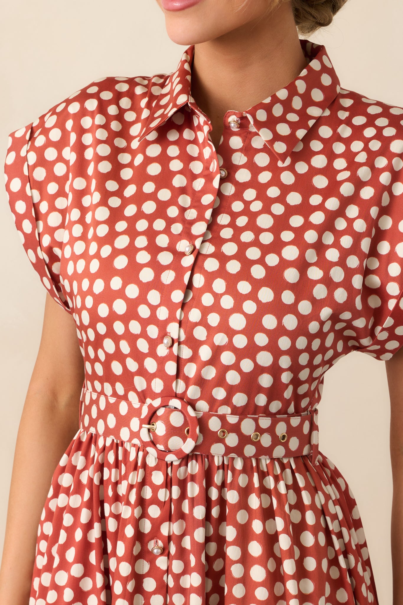 Detailed look at the ivory polka dot print, collared neckline, and button front design.