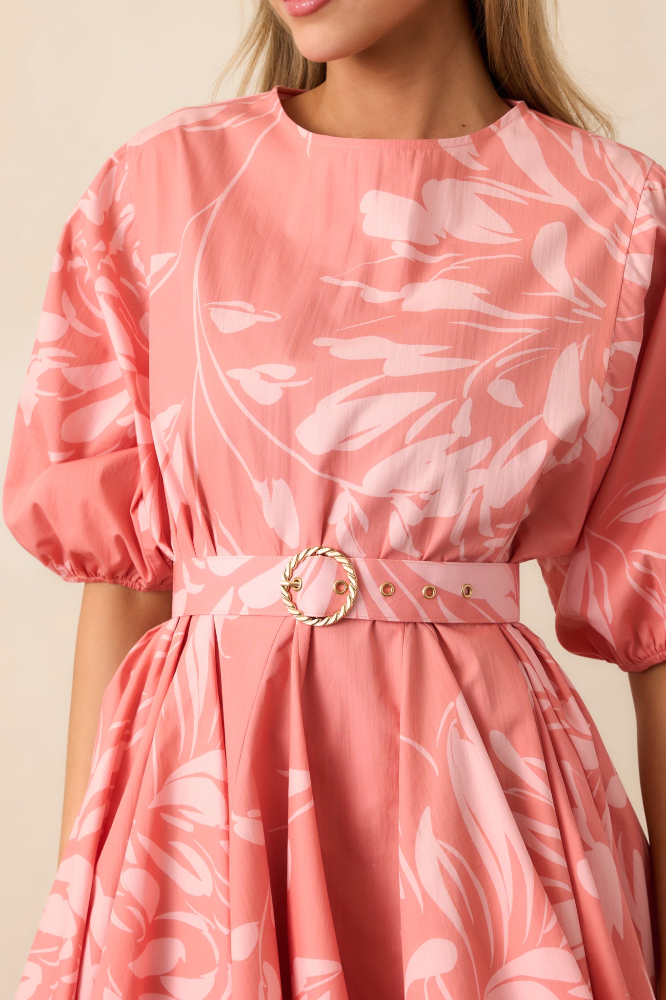 Detailed view of the rose pink and light pink floral print, belt, and elastic sleeve cuffs.