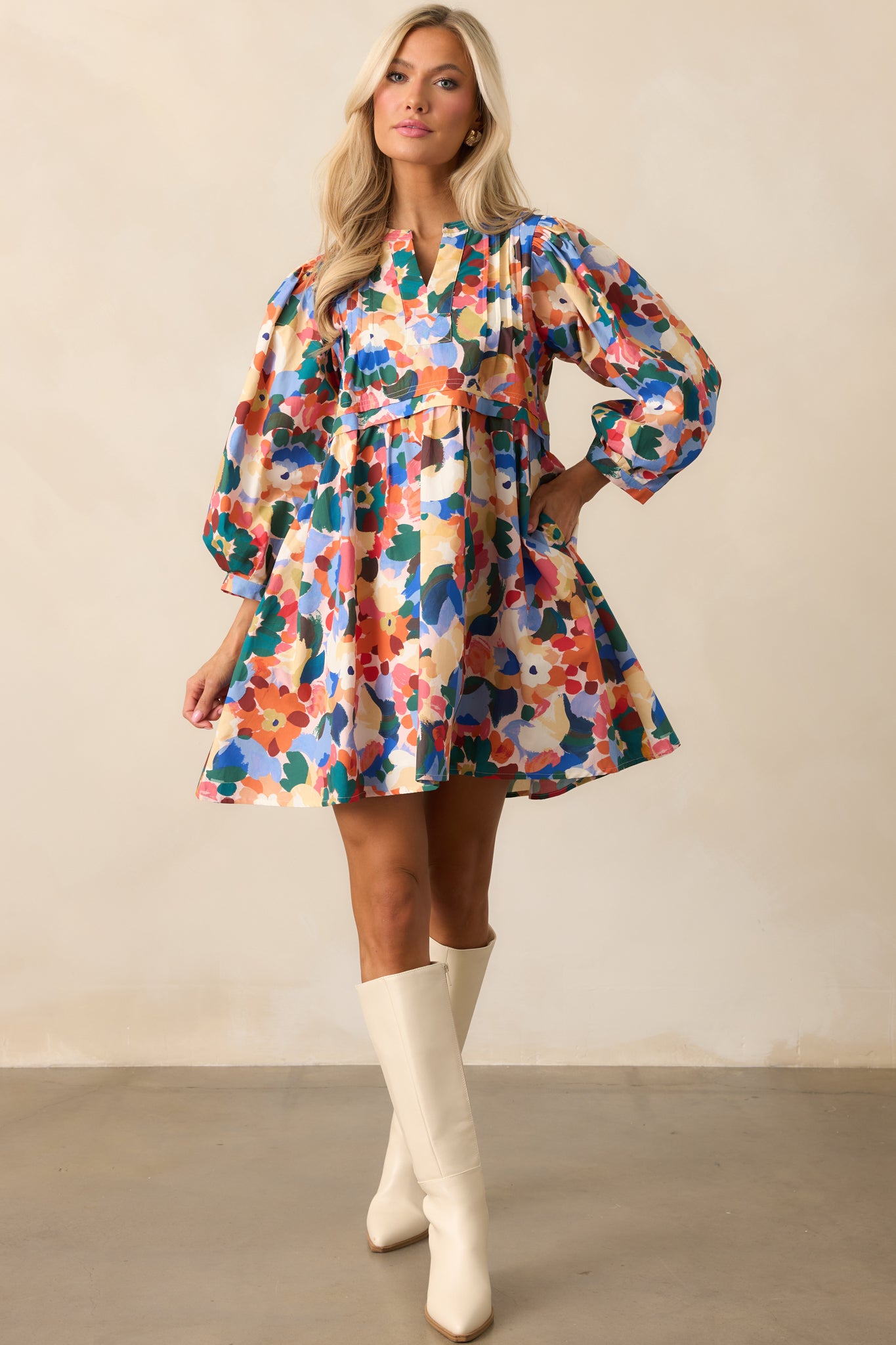 Mini dress in orange multicolor floral print with a split v-neckline and long balloon sleeves with button cuffs.