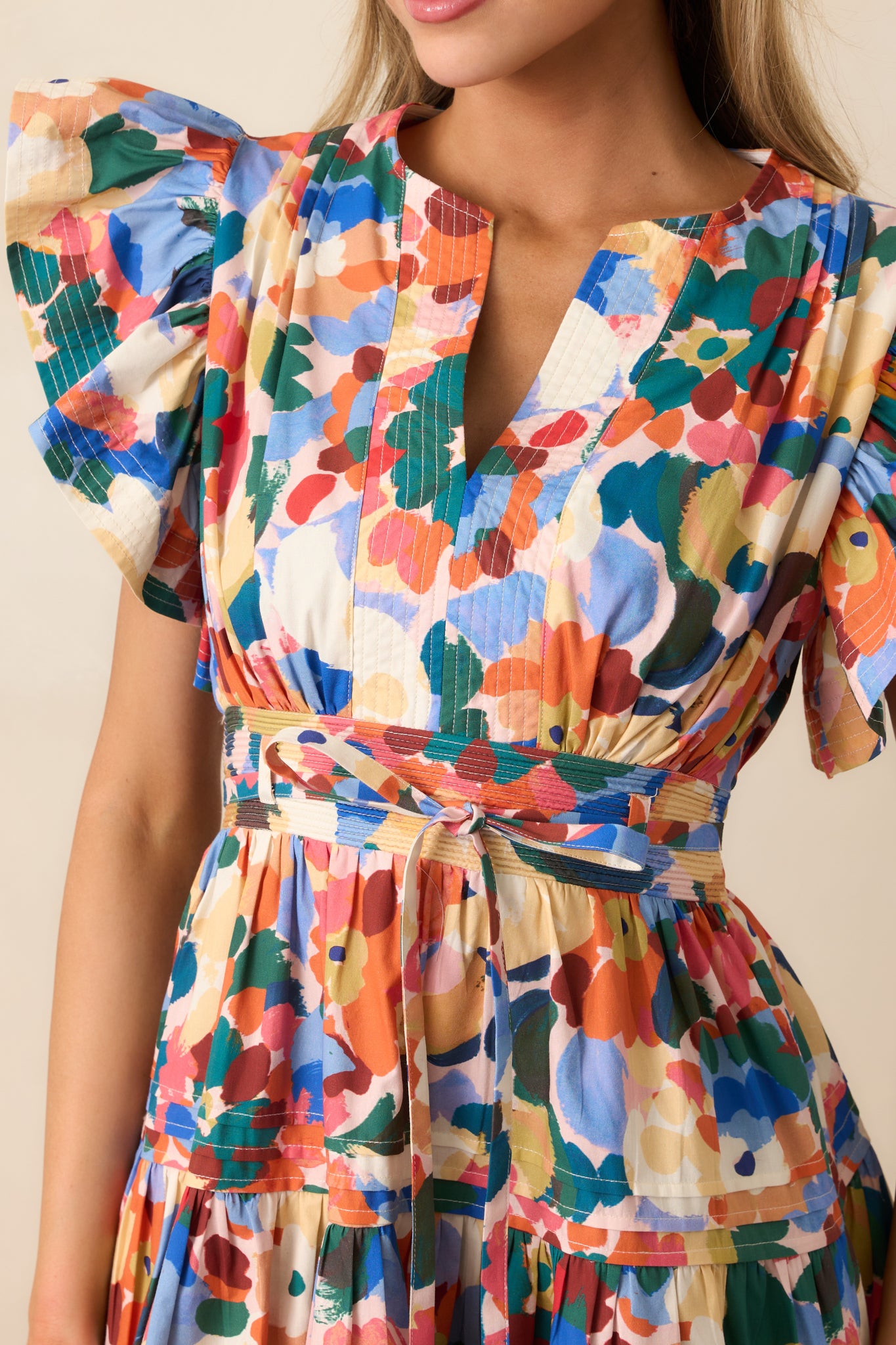 Detailed view of the multicolor floral print, split v-neckline, and pintuck skirt details.