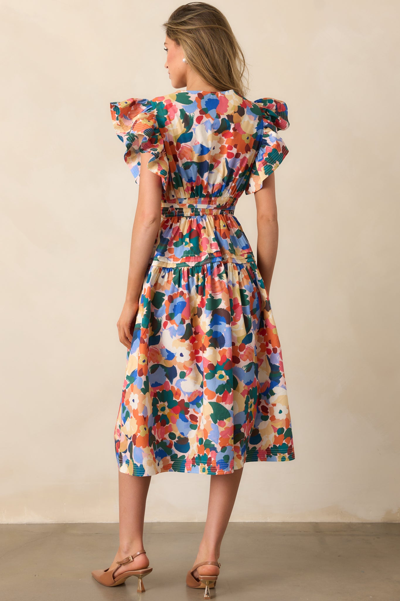 Rear view of the midi dress highlighting the smocked back waist, tiered skirt, and ruffle sleeves.