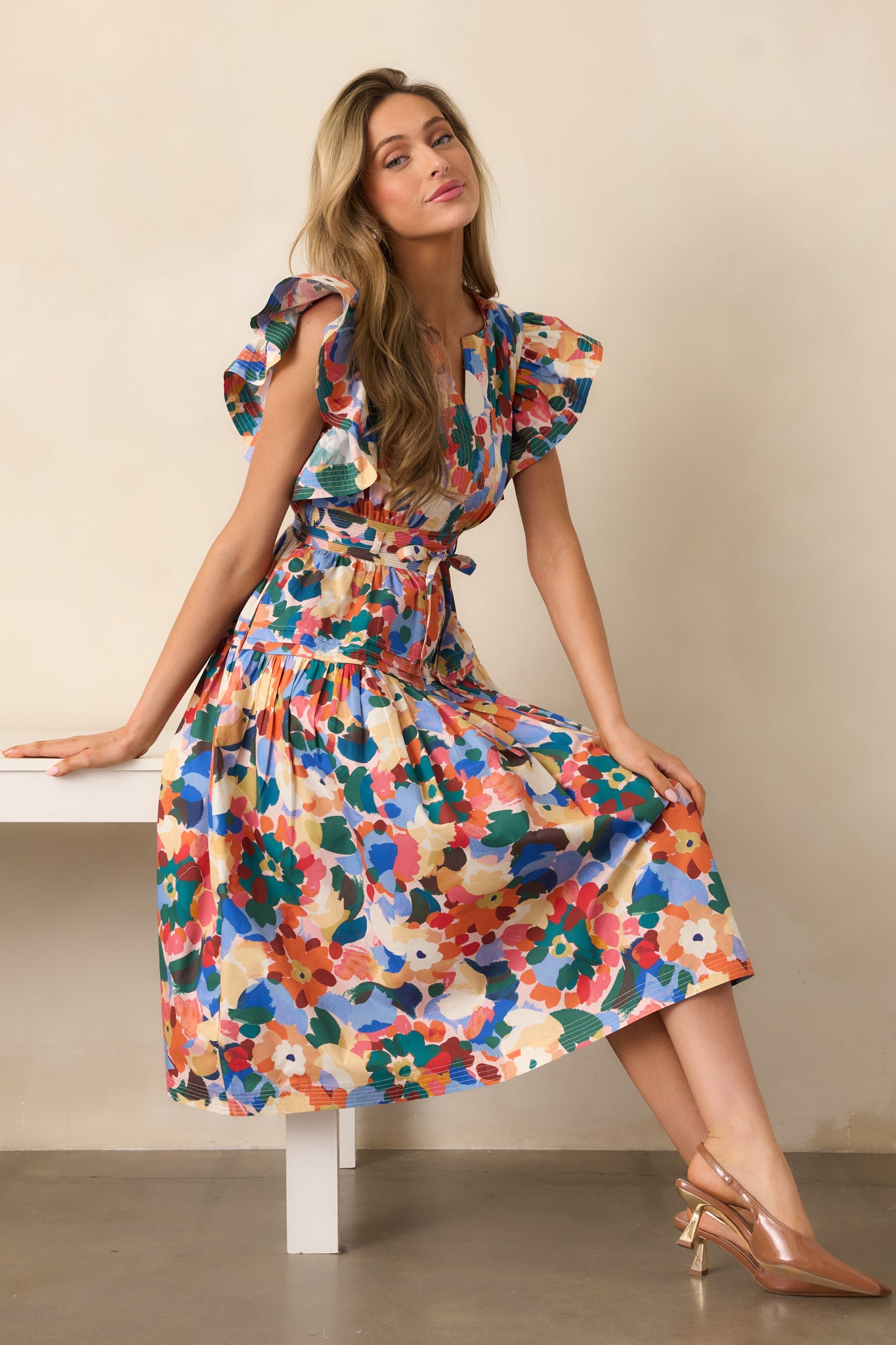Orange multicolor floral midi dress with a split v-neckline, short ruffle sleeves, and a tiered skirt.