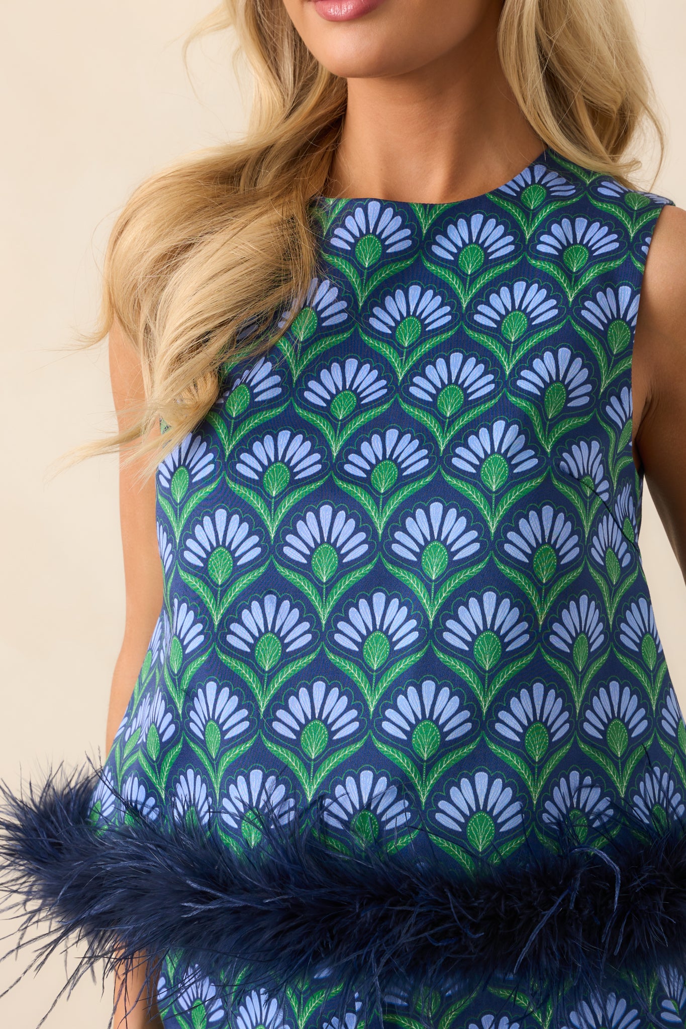 Extreme close-up showing the blue multicolor geometric print and feather trim at the bottom hem of the sleeveless top.