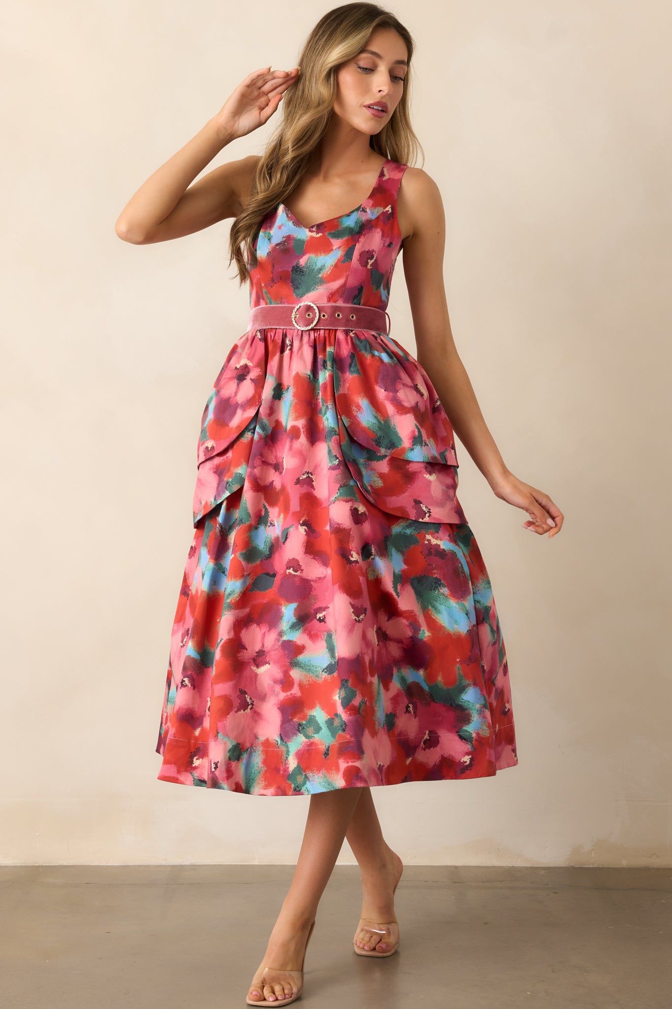 Pink watercolor floral midi dress styled to showcase its sleeveless design, scoop neckline, and tiered peplum overskirts.