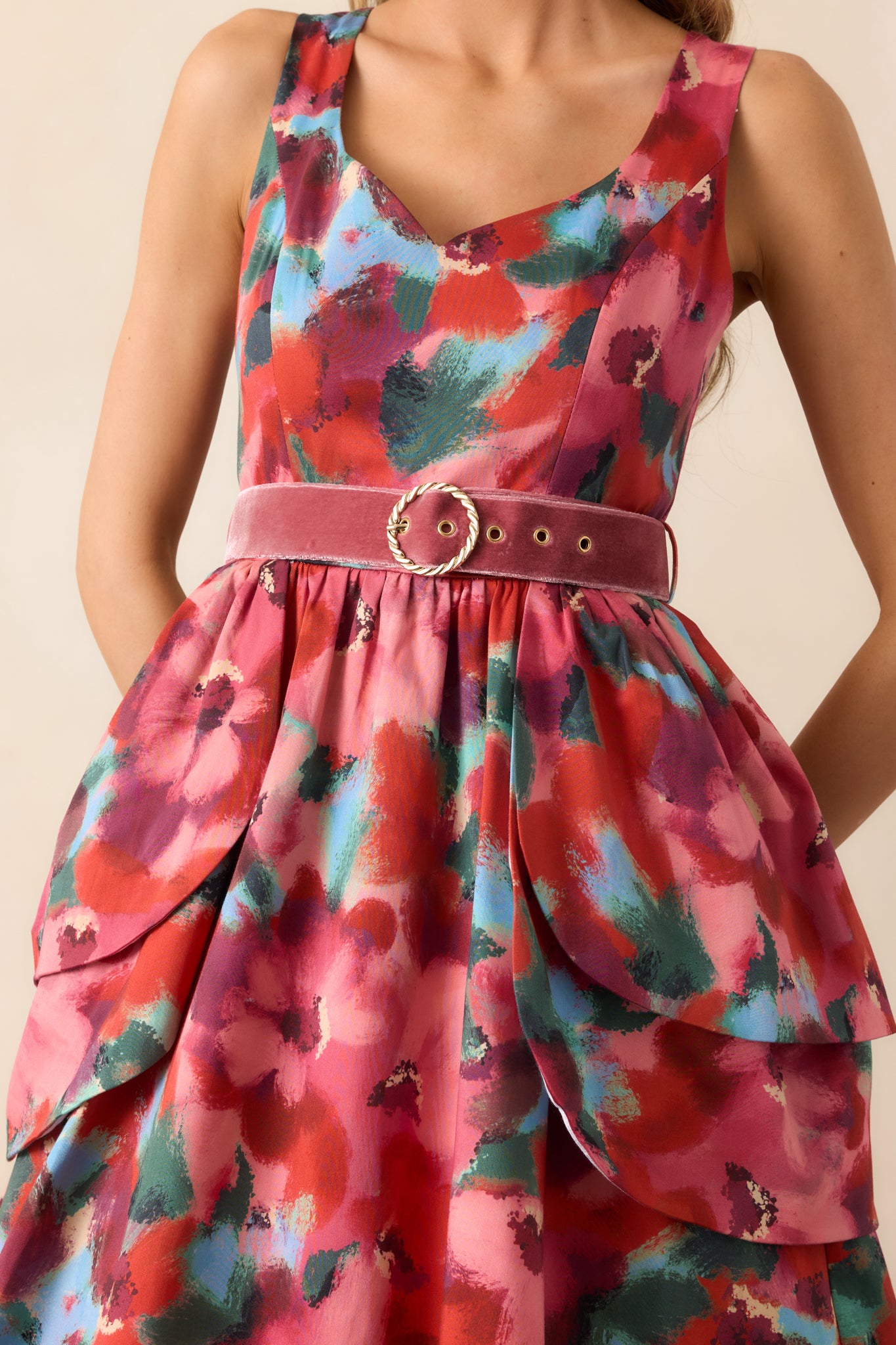 Close-up of the velvet belt with gold buckle and layered peplum overskirts showing fabric texture and floral print.