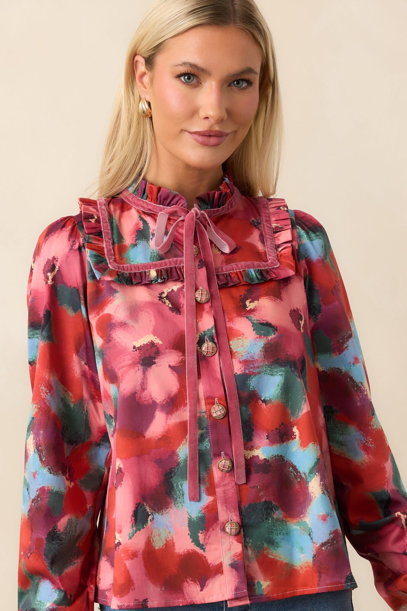 Detail crop showing the ruffle cuffs on long puff sleeves and straight hem of the pink floral top.