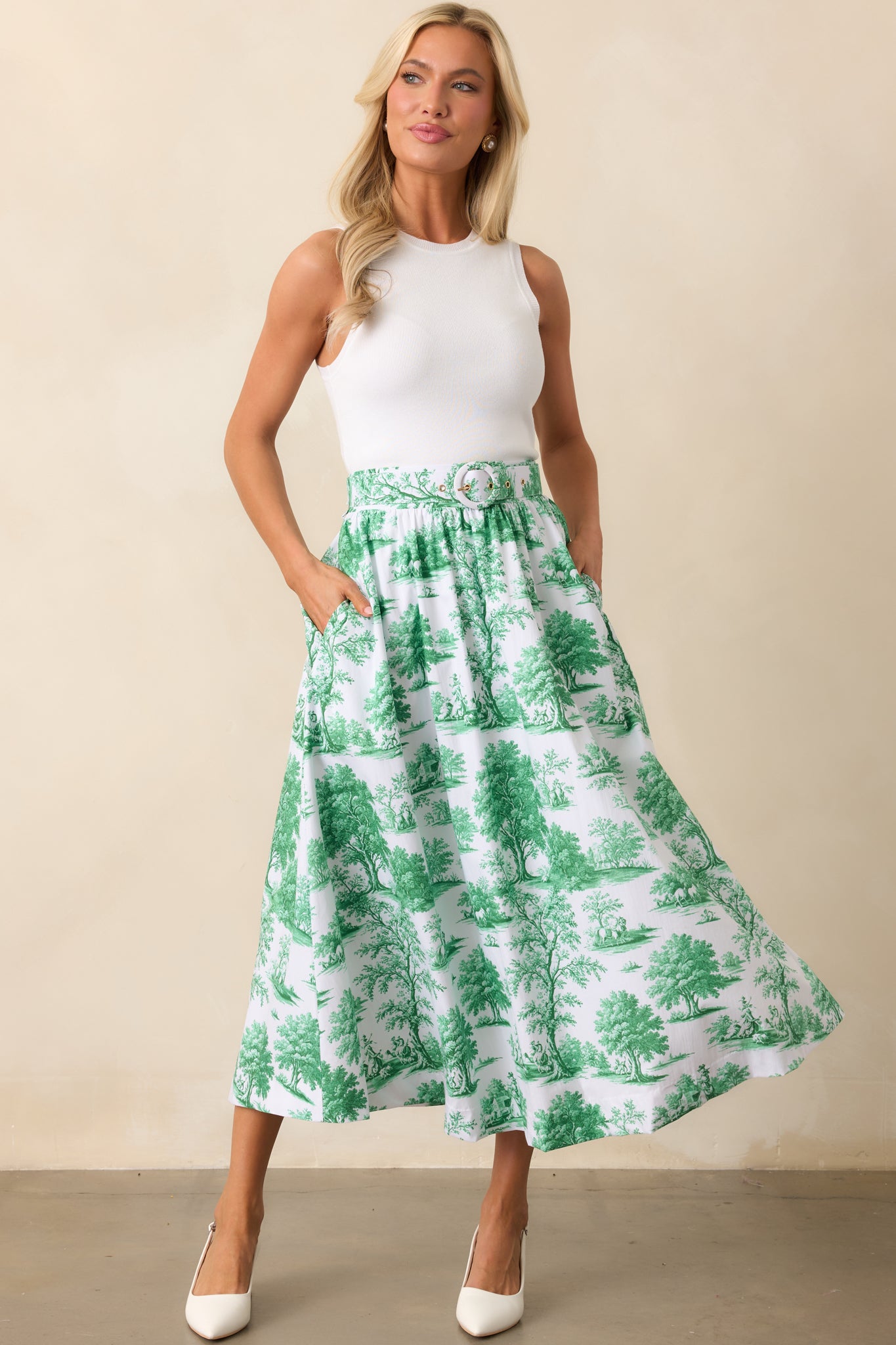 An eden green midi skirt featuring a delicate toile print, elastic waist insert for a comfortable fit, and functional pockets for added convenience.